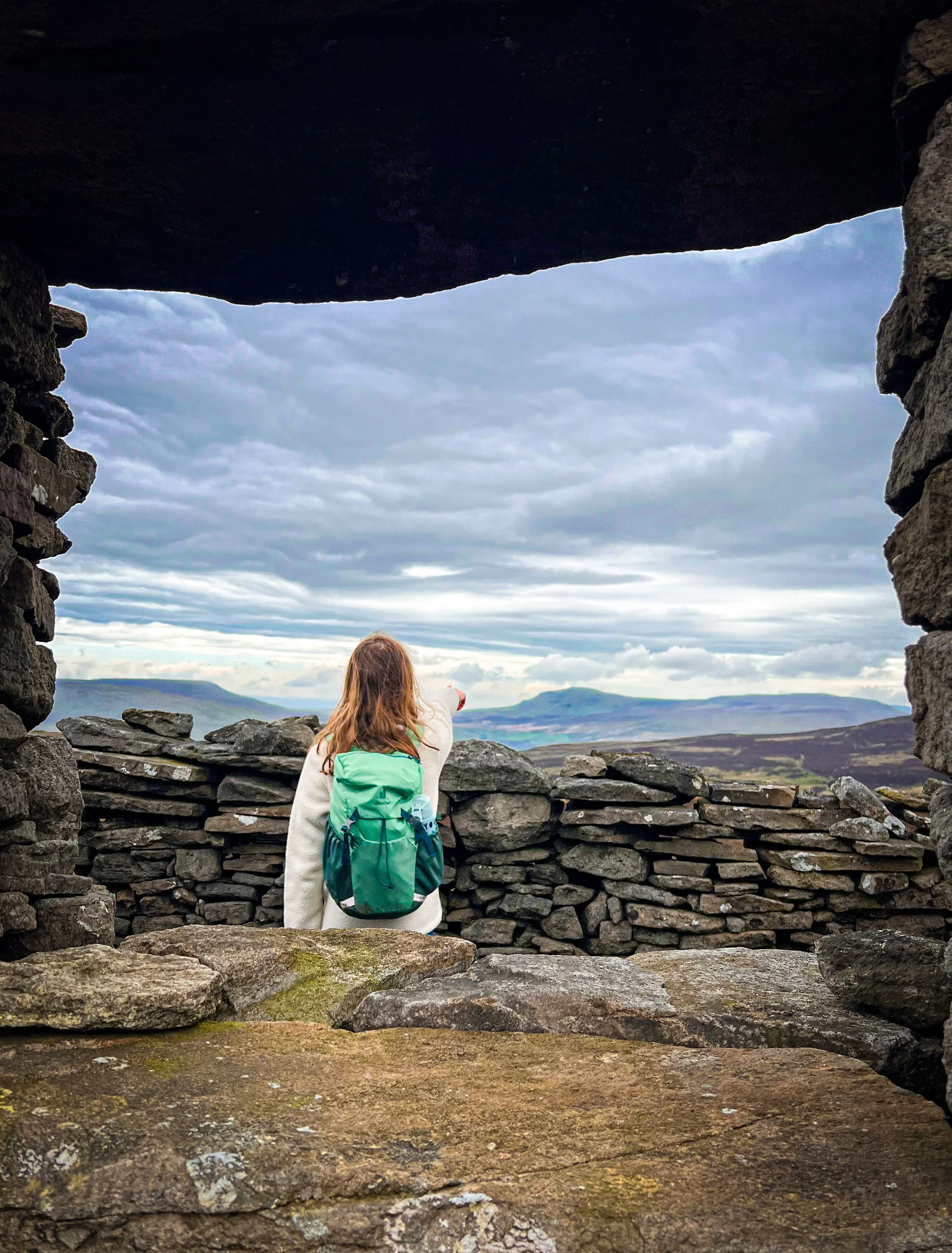 Child standing in ruined building pointing towards mountains in distance