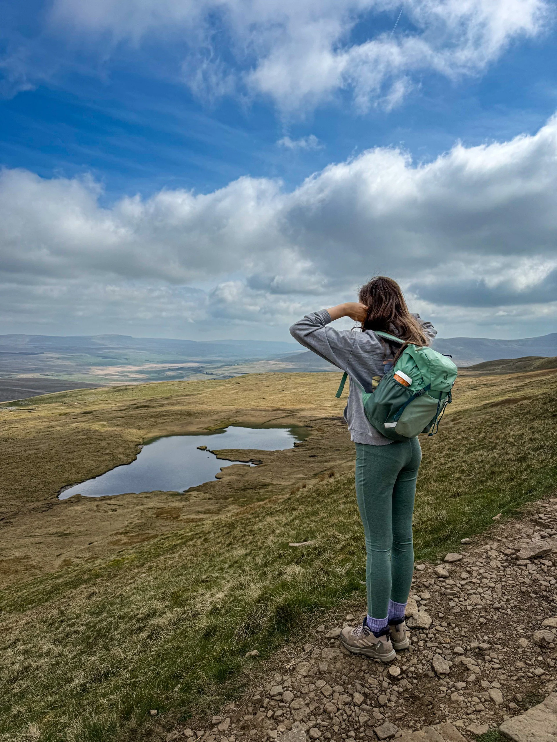 child standing on the side of Whernside mountain with tarns in the background