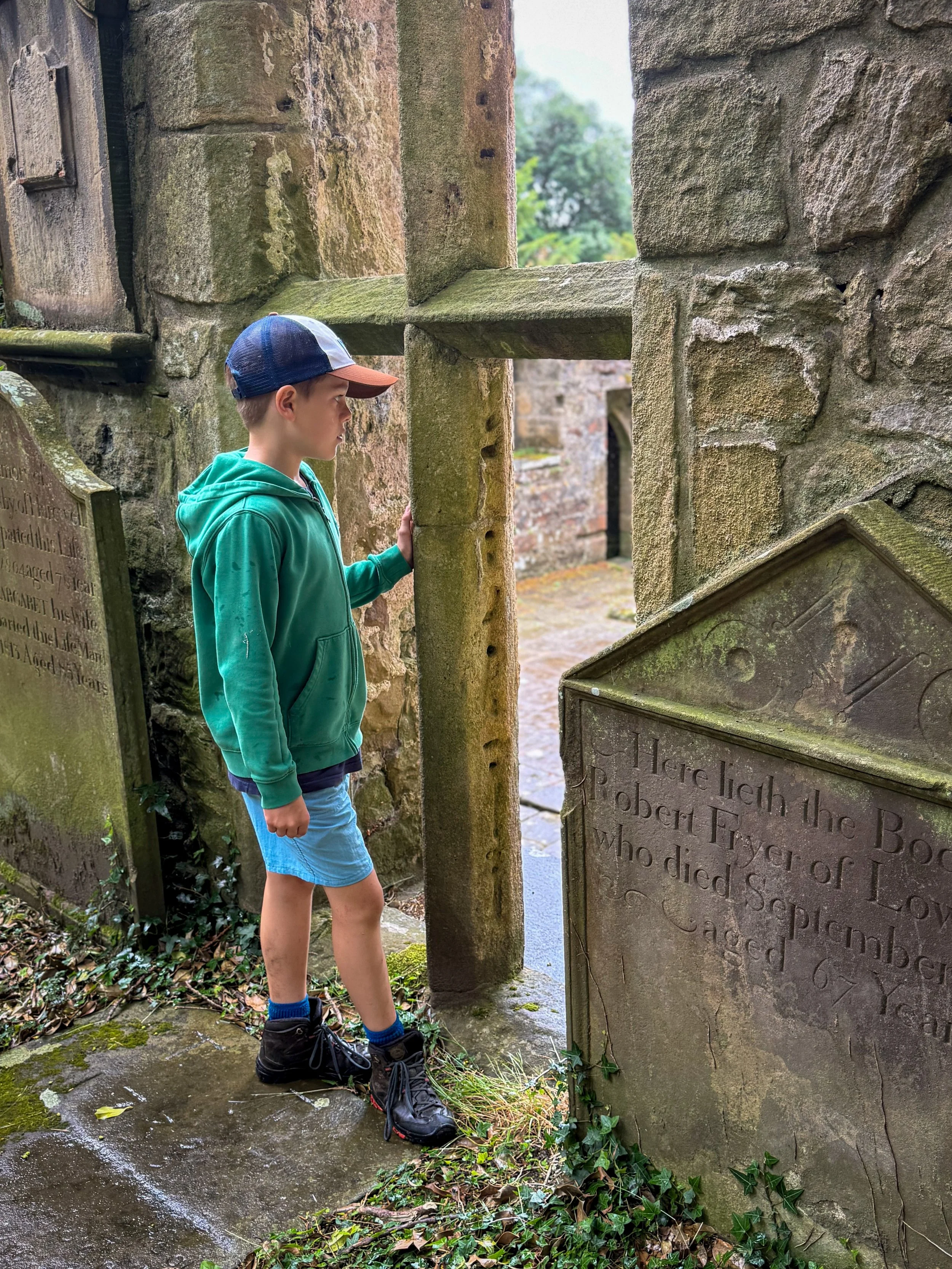 Child standing next to a gravestone looing into an old church window