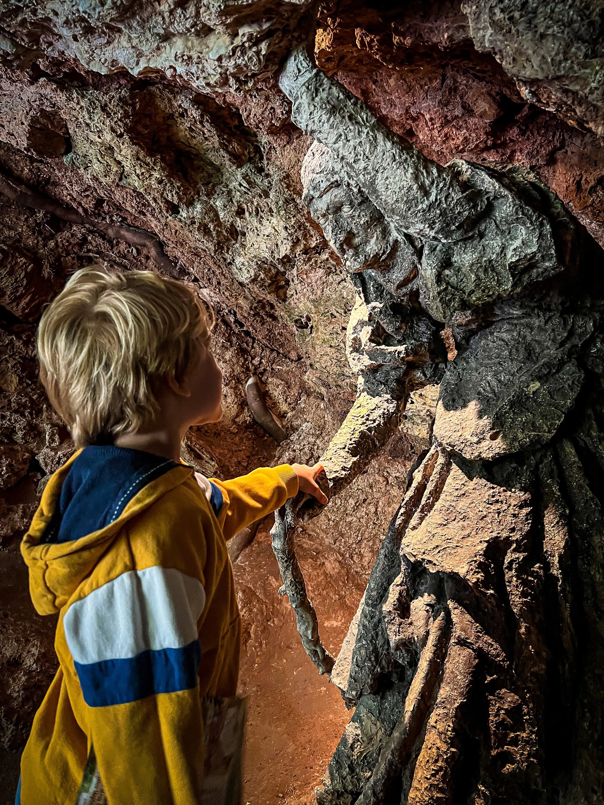 Child holding the hand of a witch statue in a cave