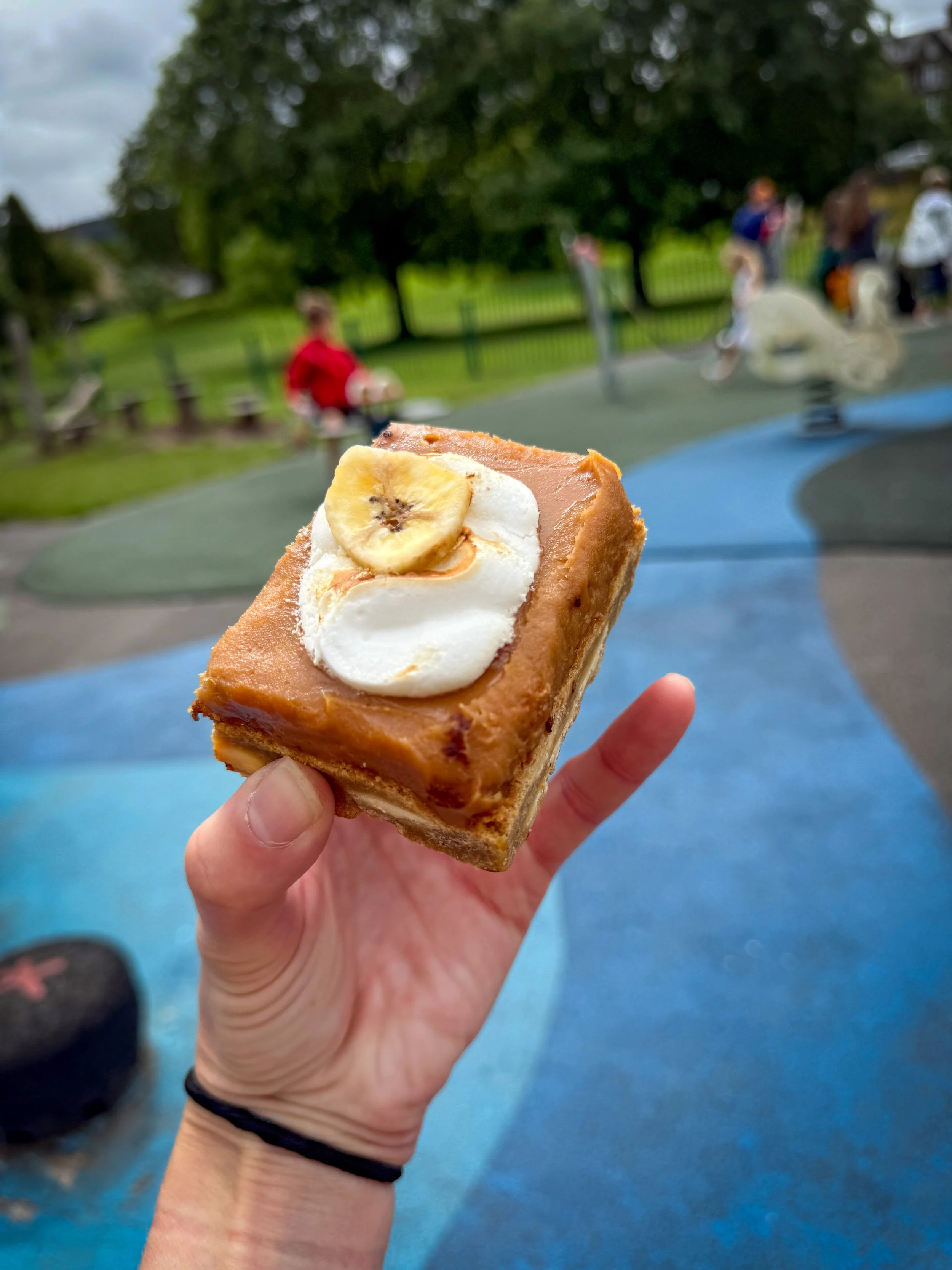 a hand holding a cake with a dried banana on top