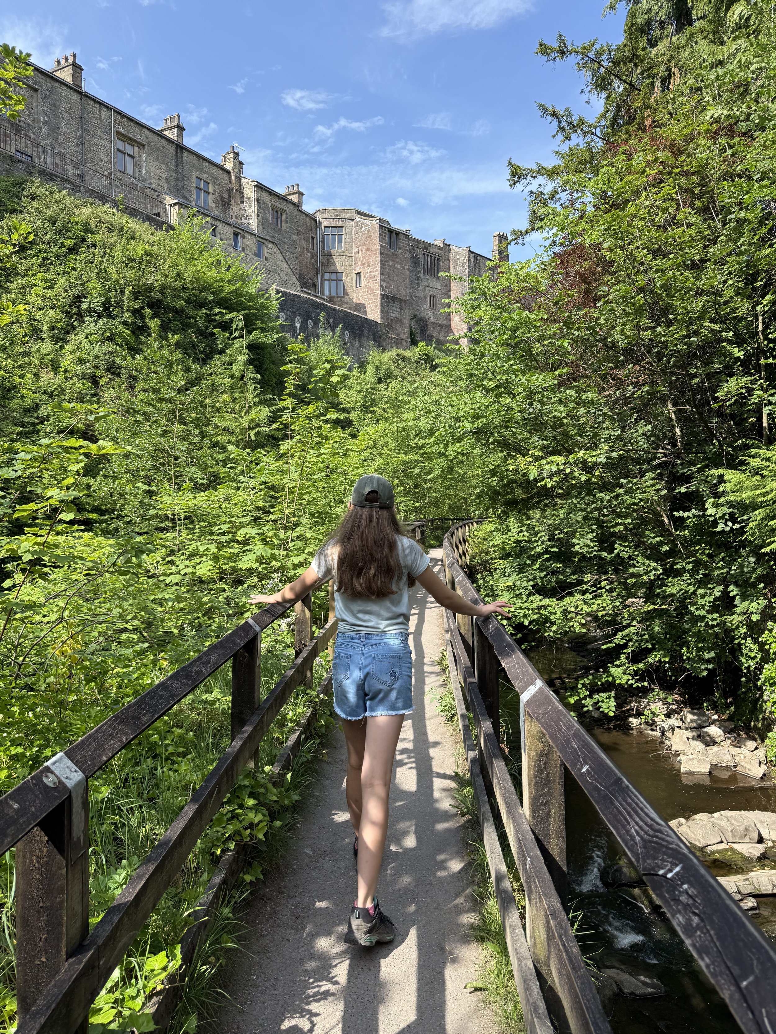 Child walking along walkway with castle in the distance and trees either side