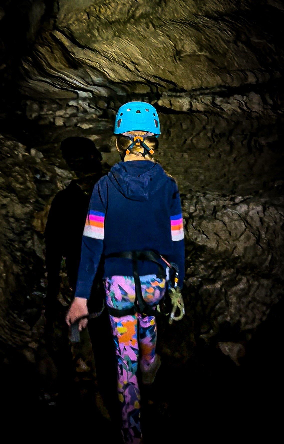 Child wearing a helmet walking through a dark tunnel