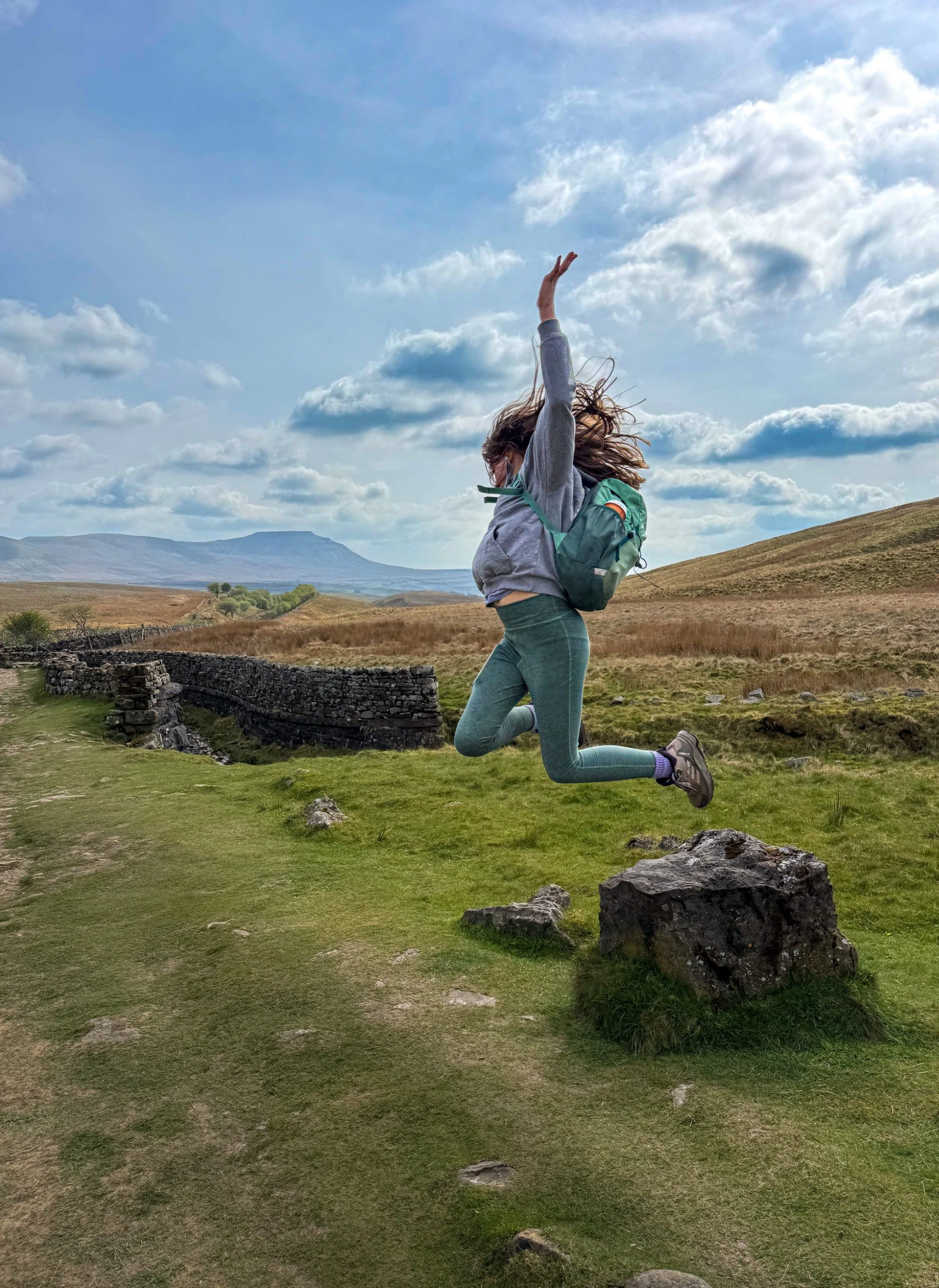 Jumping off a rock with Ingleborough in the background