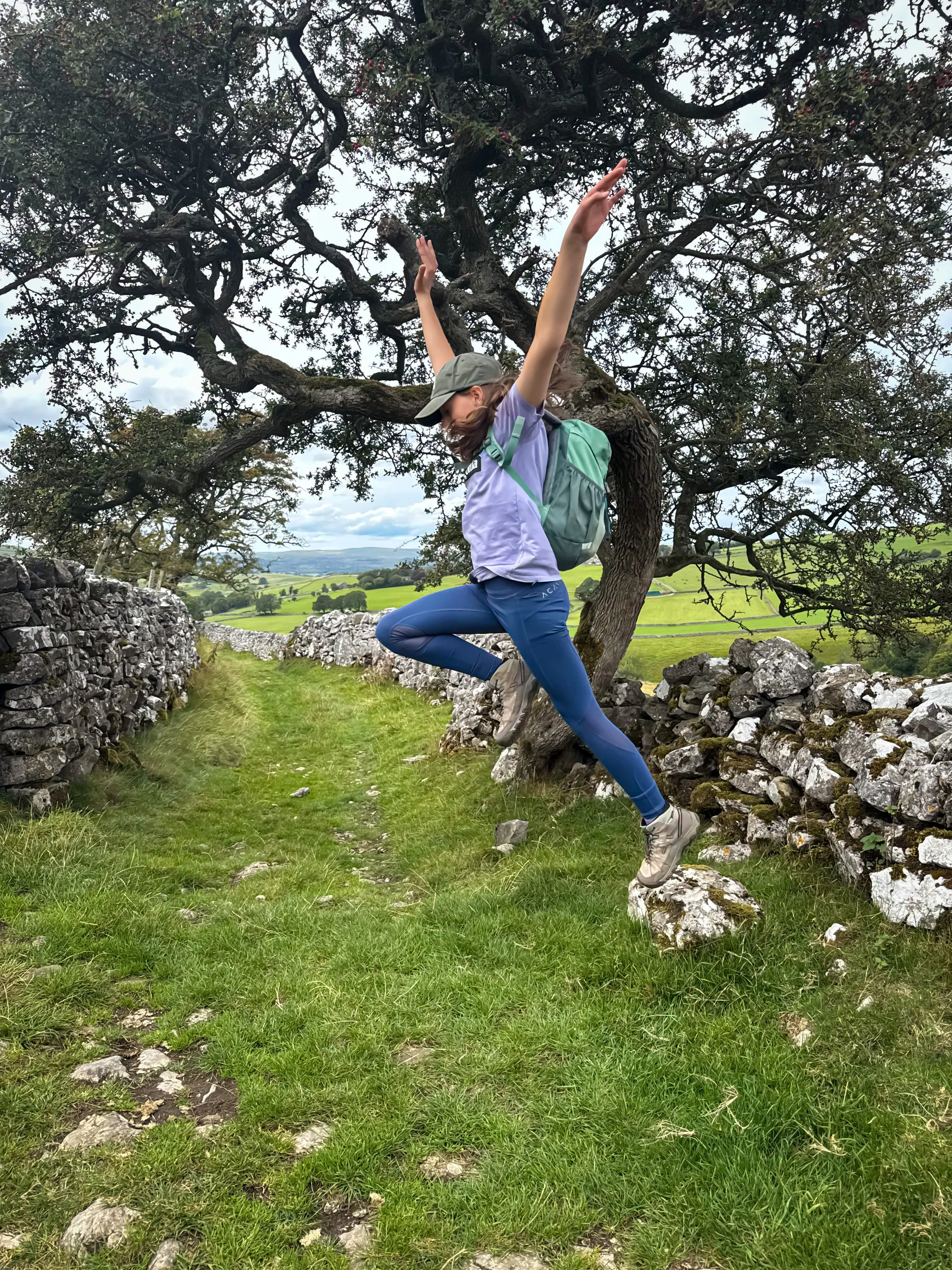 Child leaping in the air on a walled country lane