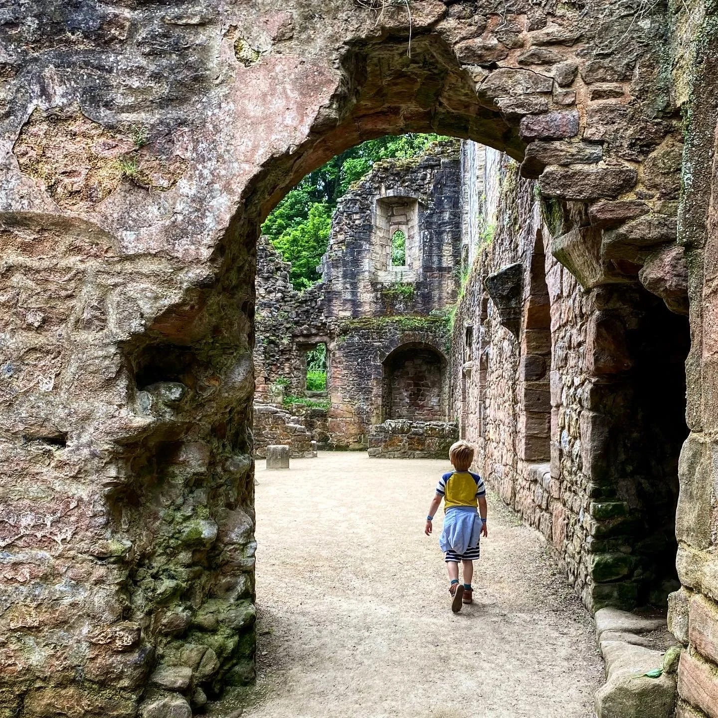 child walking through an archway of a ruined castle