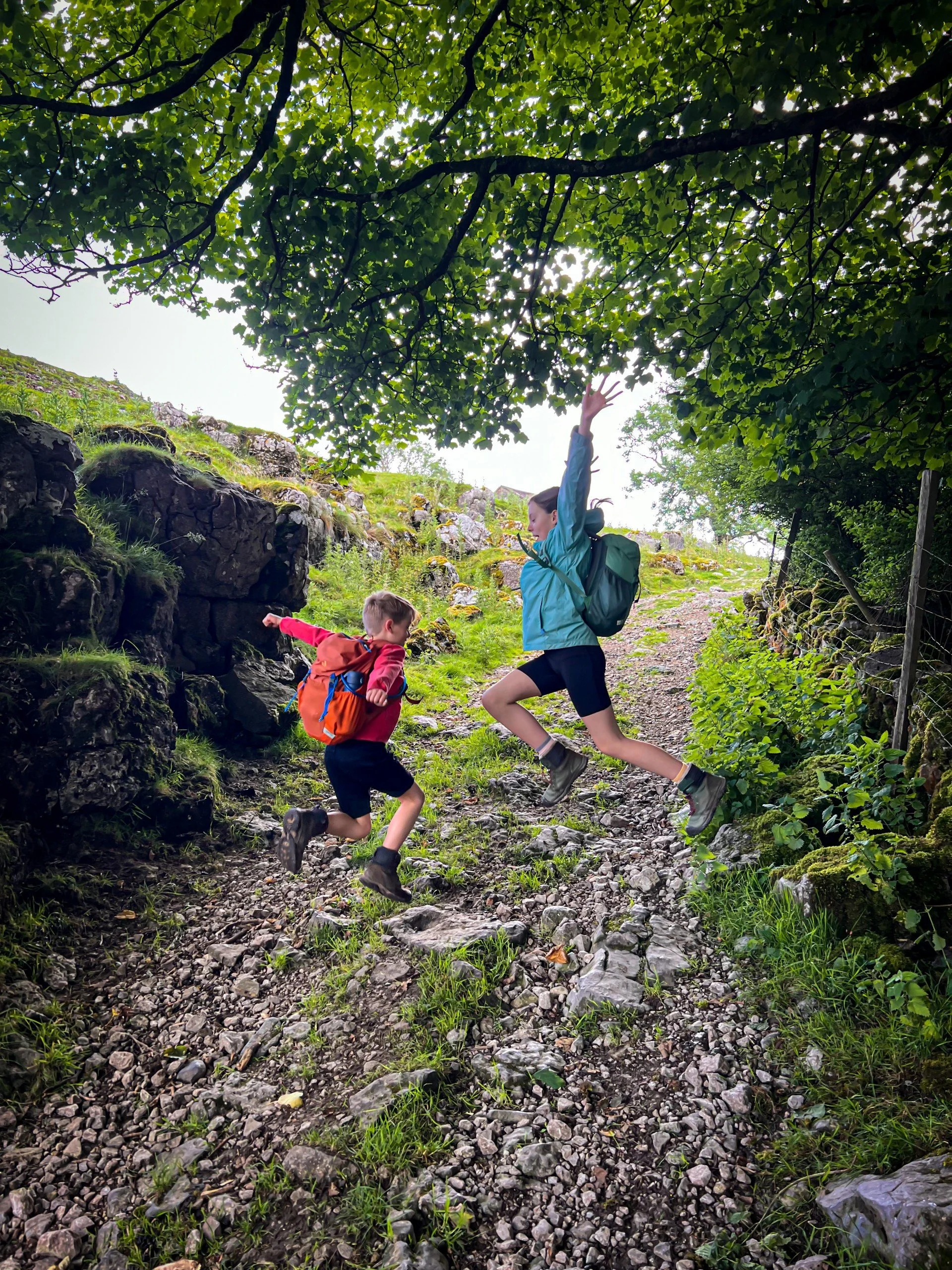 Two children leaping in the air on a stone track