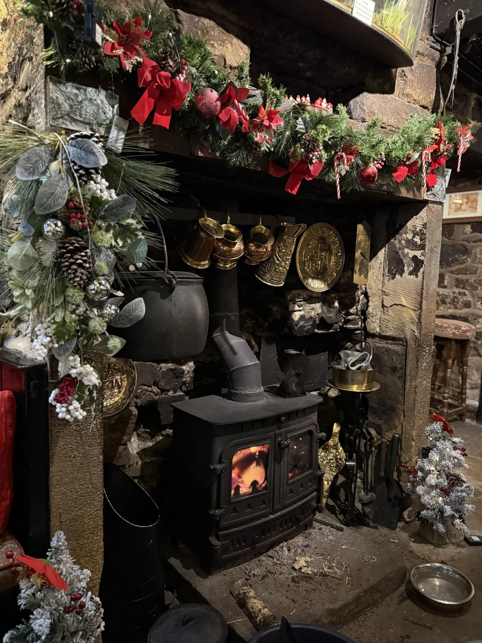 The fireplace of a pub decorated with Christmas decorations around a roaring fire