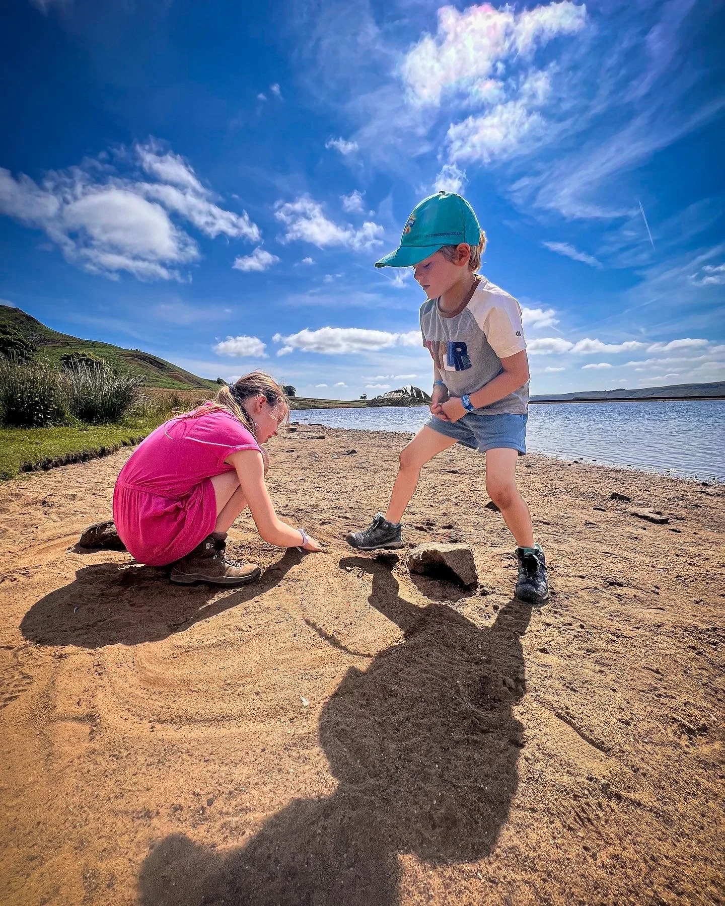 Children playing in the sand next to reservoir