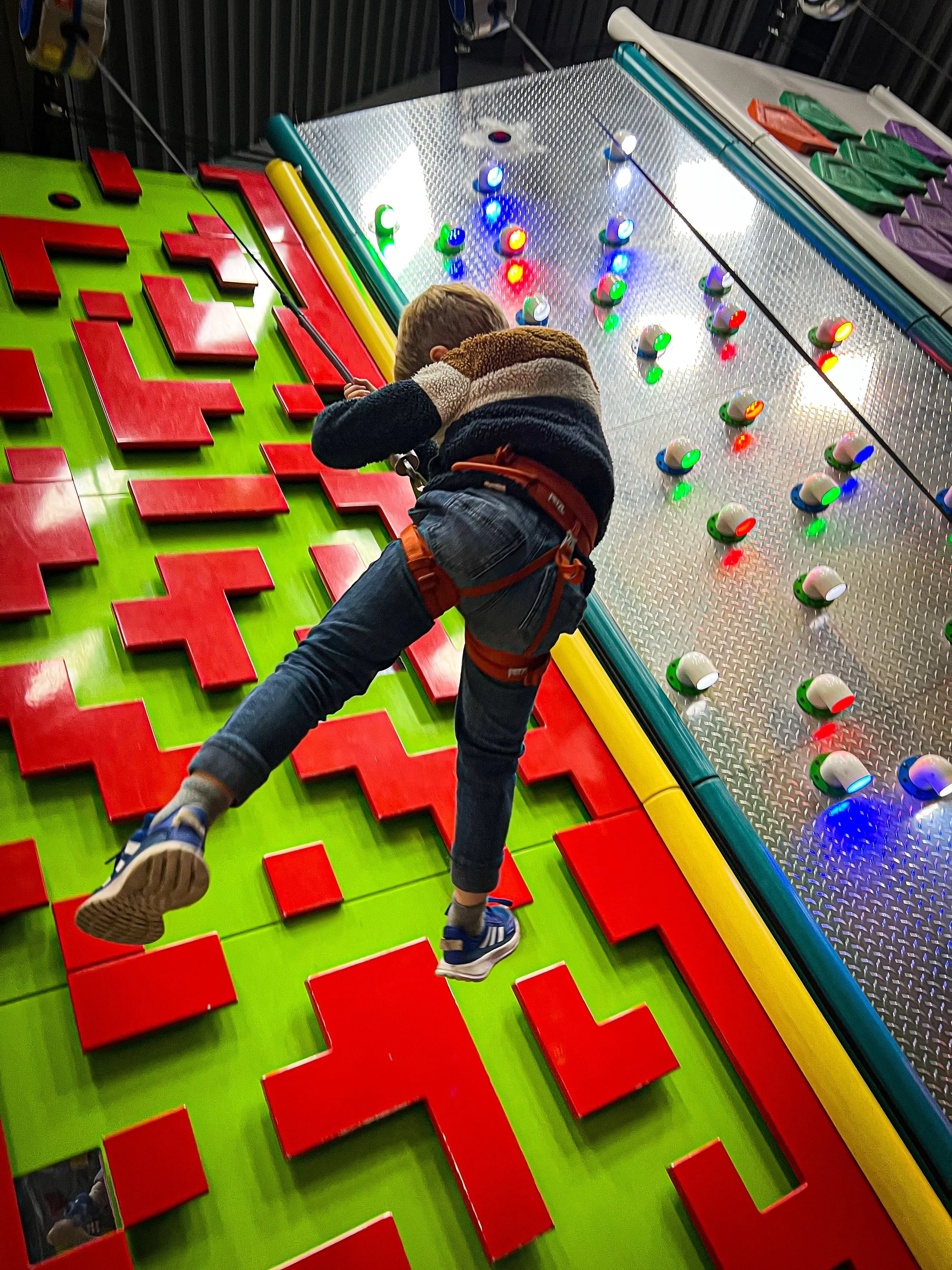 Child climbing down a brightly coloured climbing wall