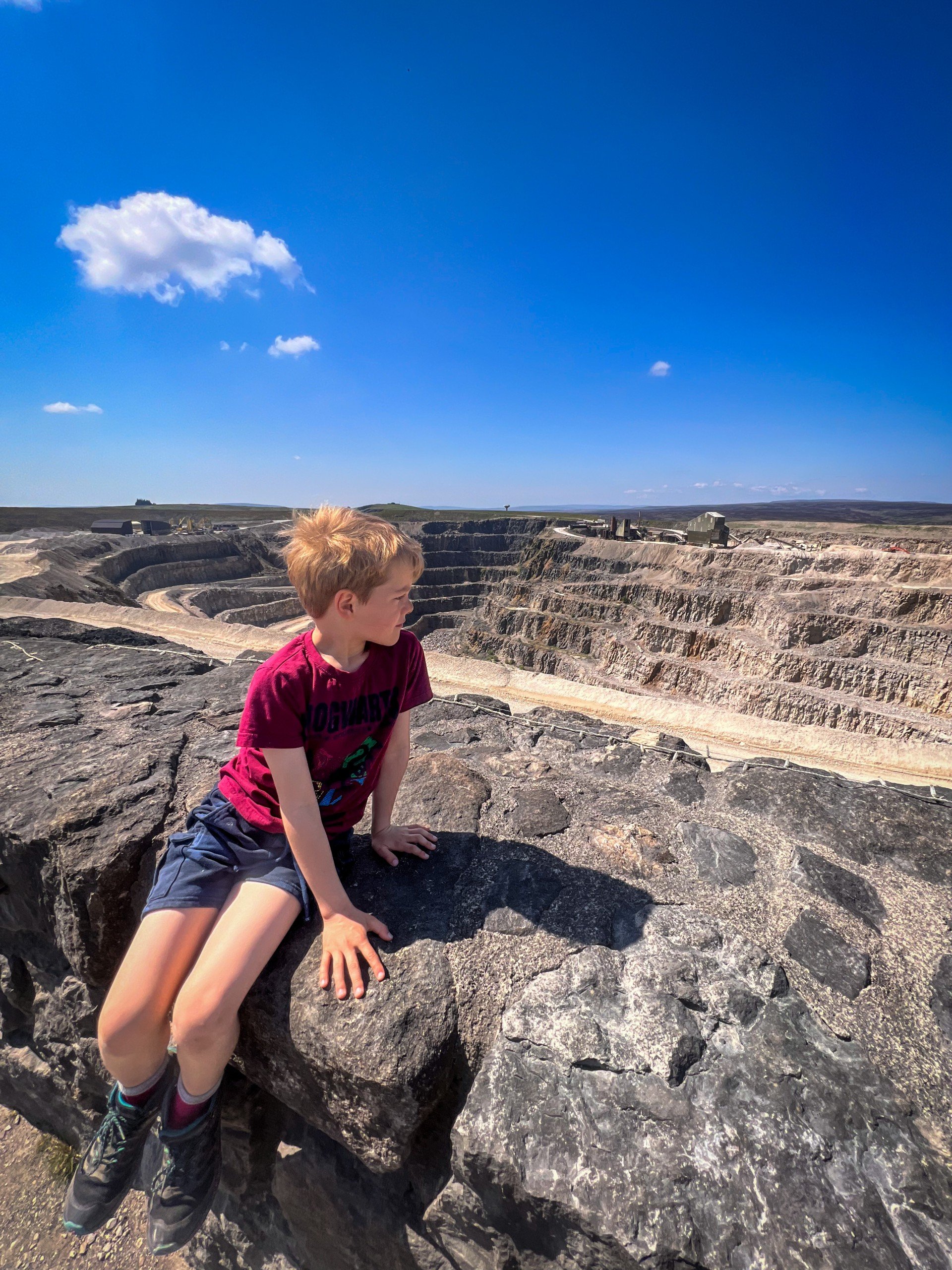 Child sitting on top of a wall looking over a quarry
