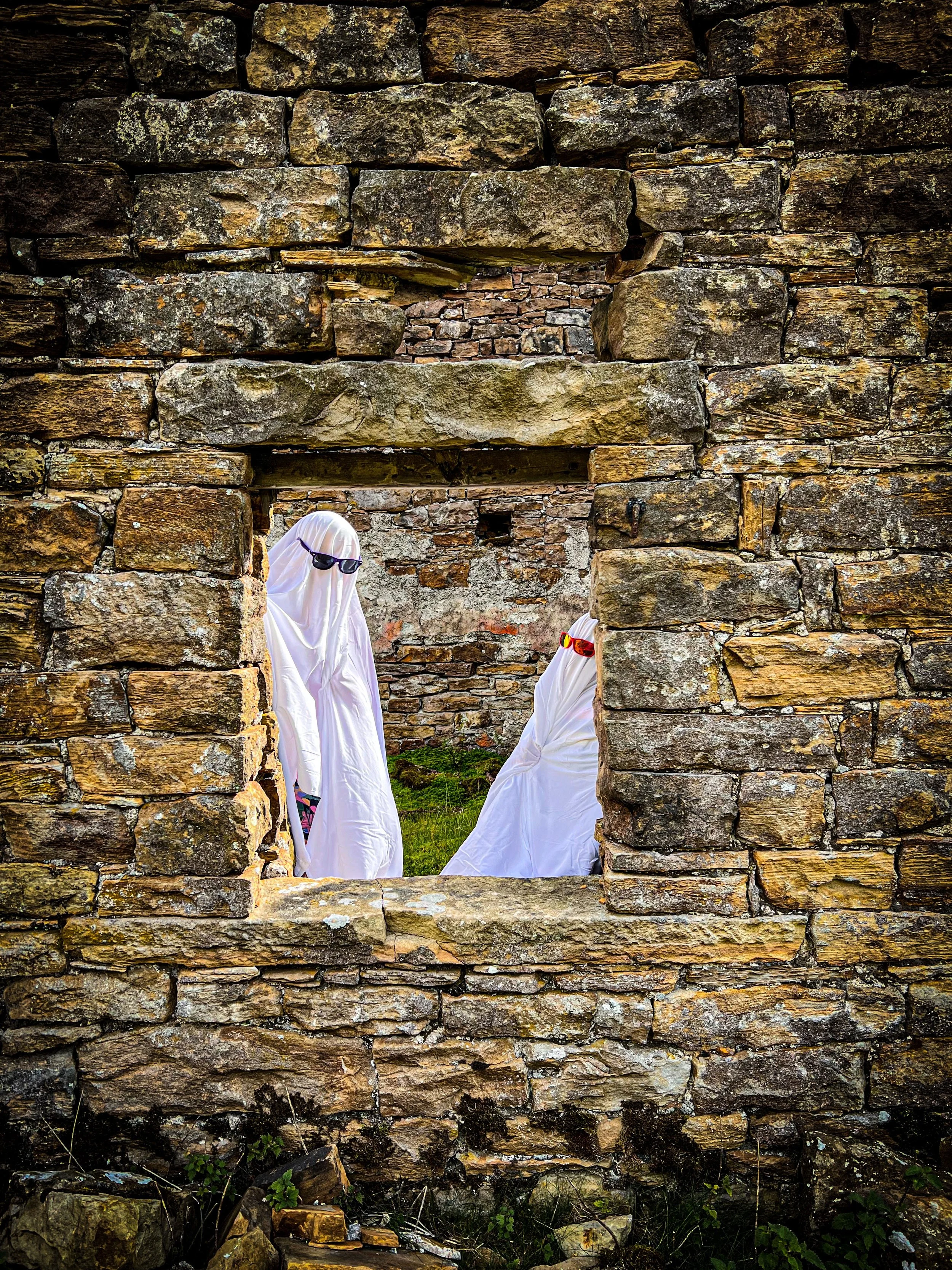 Twho childresn dresed as ghosts peering through a window