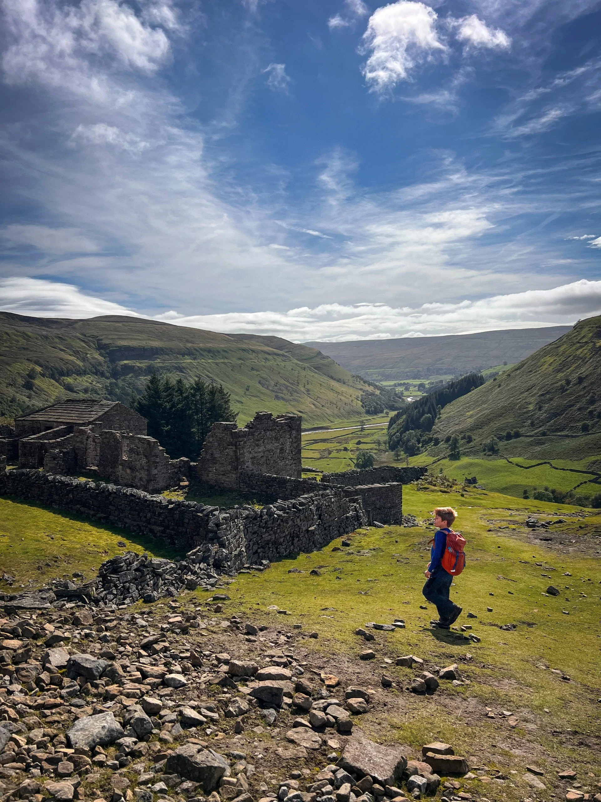 Child standing in front of the ruins of an old farm building
