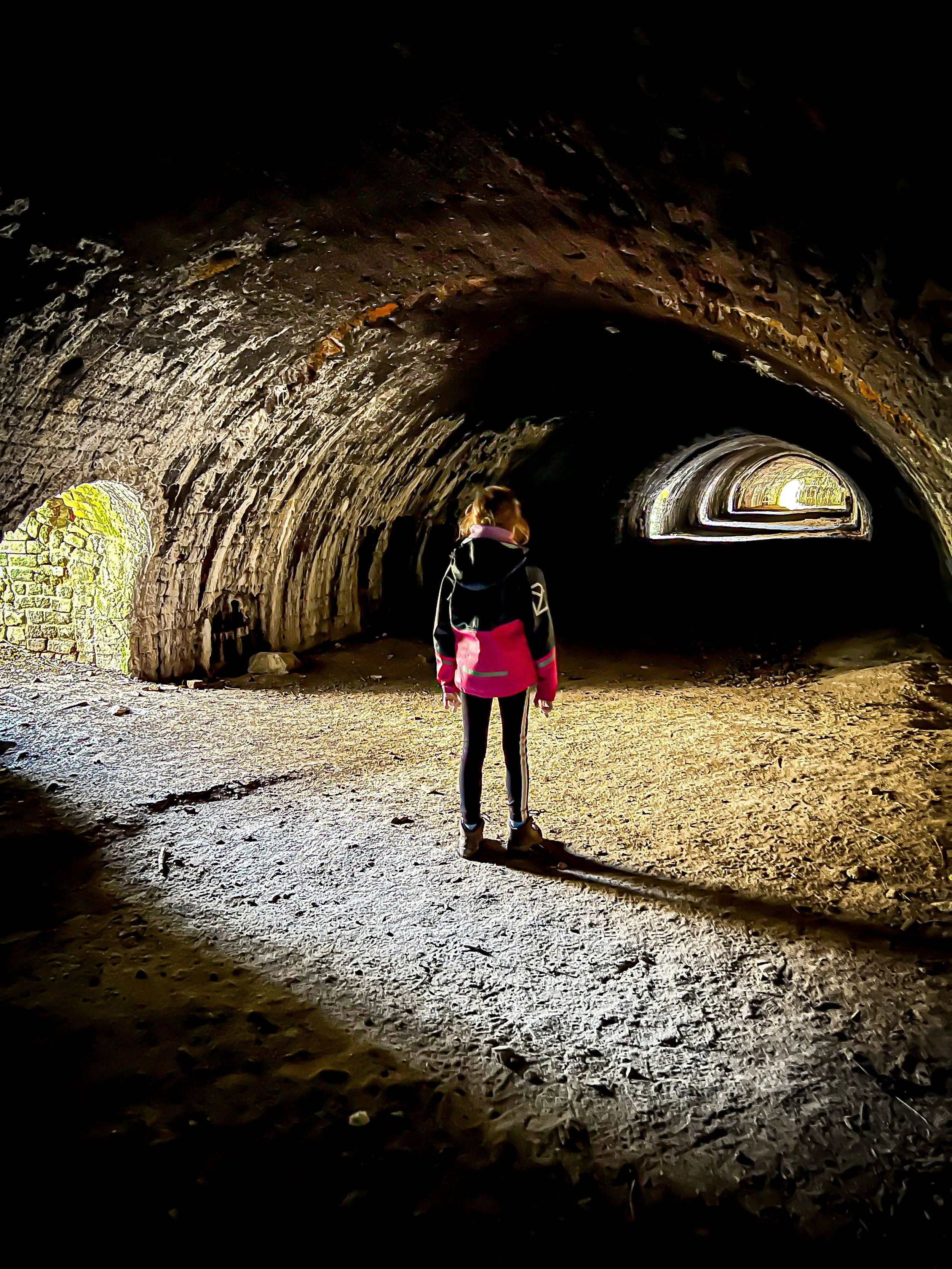 Child standing in an industrial lime kiln wearing a pink coat