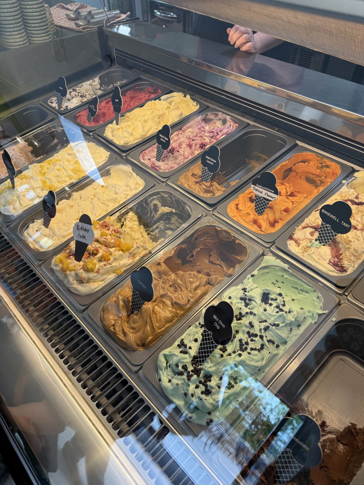 An ice cream parlous selection of flavours with lots of ice cream in tubs in a freezer