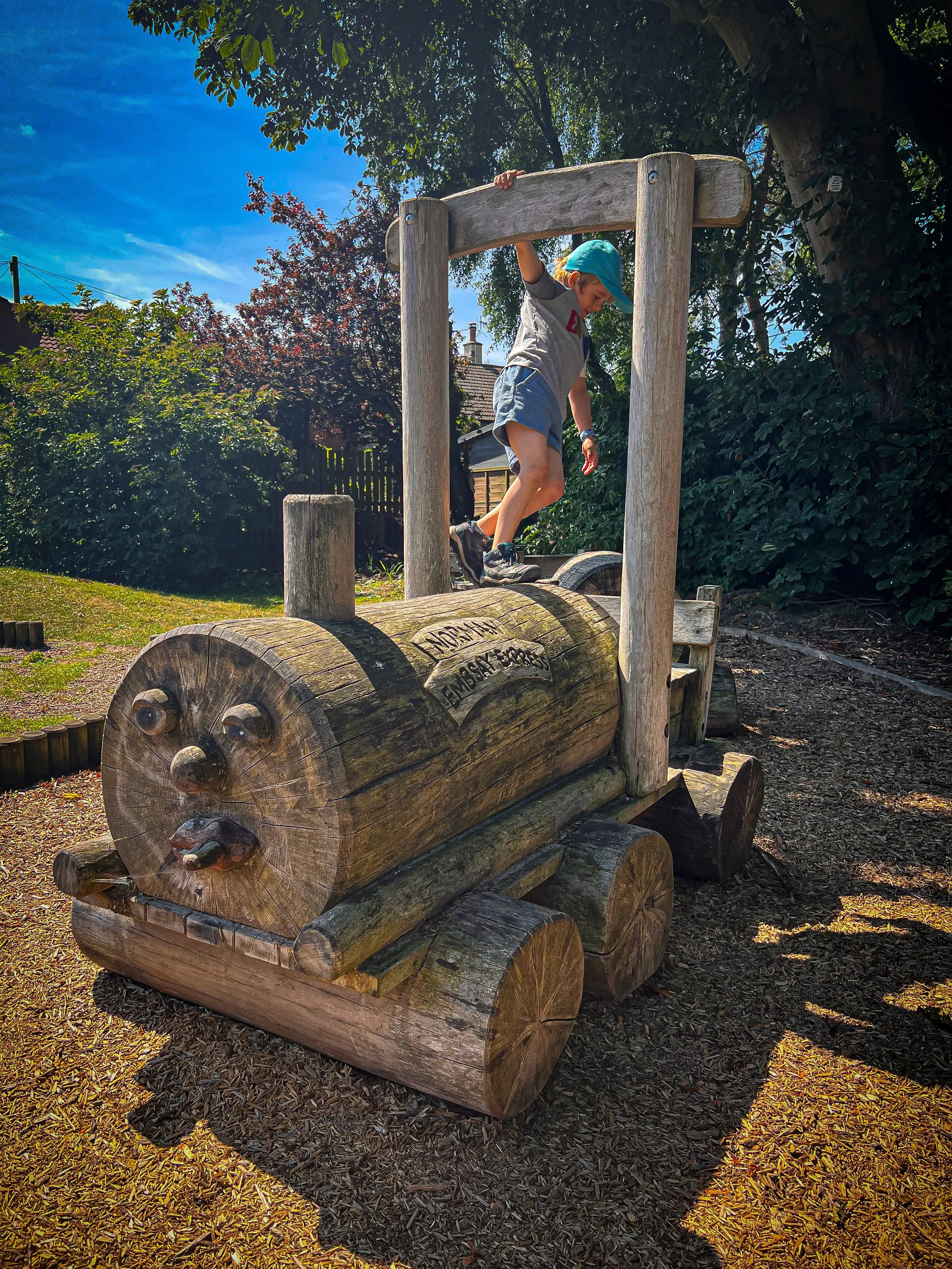 Child standing on a wooden train in the sunshine