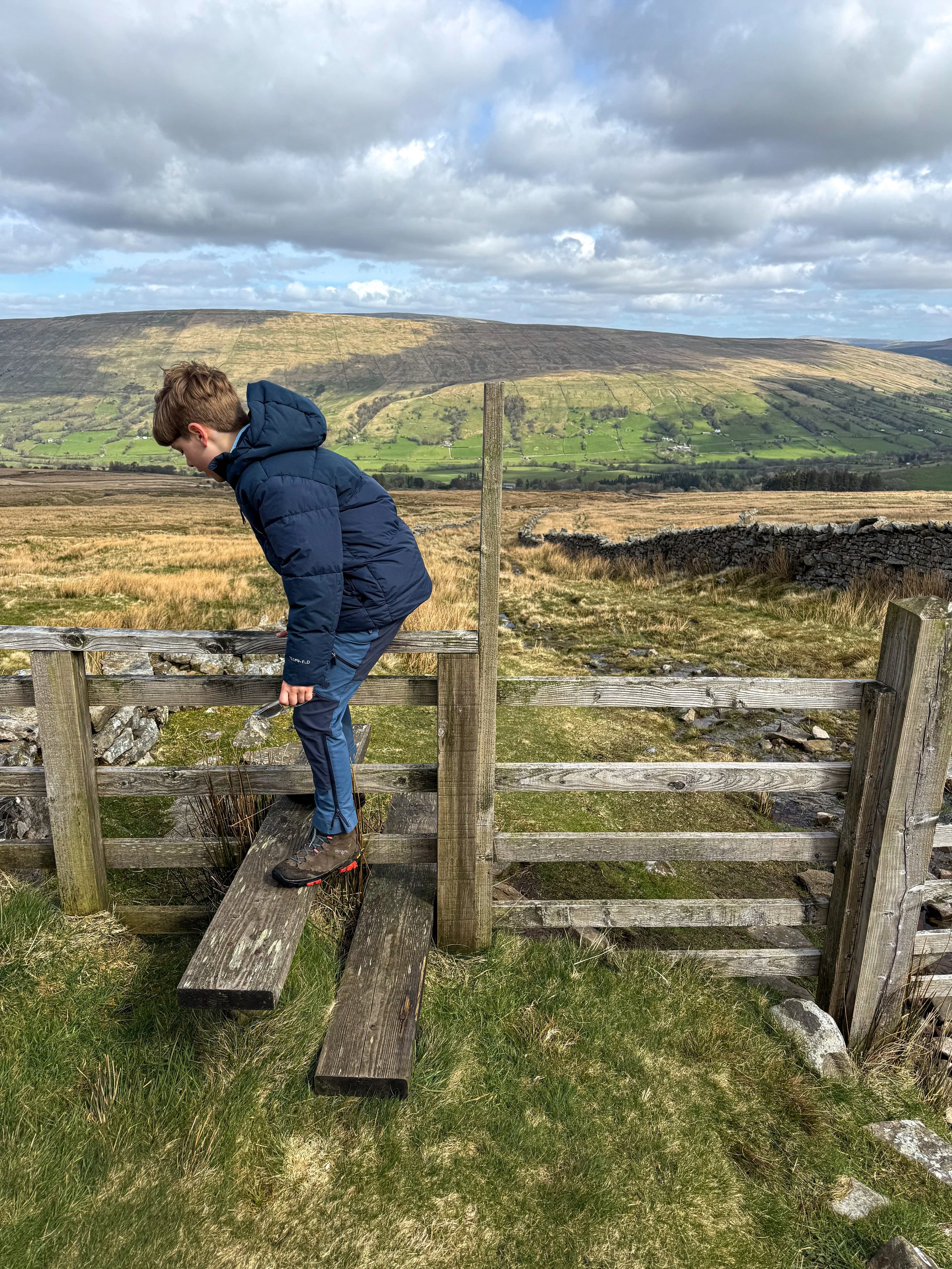 child climbing over a stile with views ahead