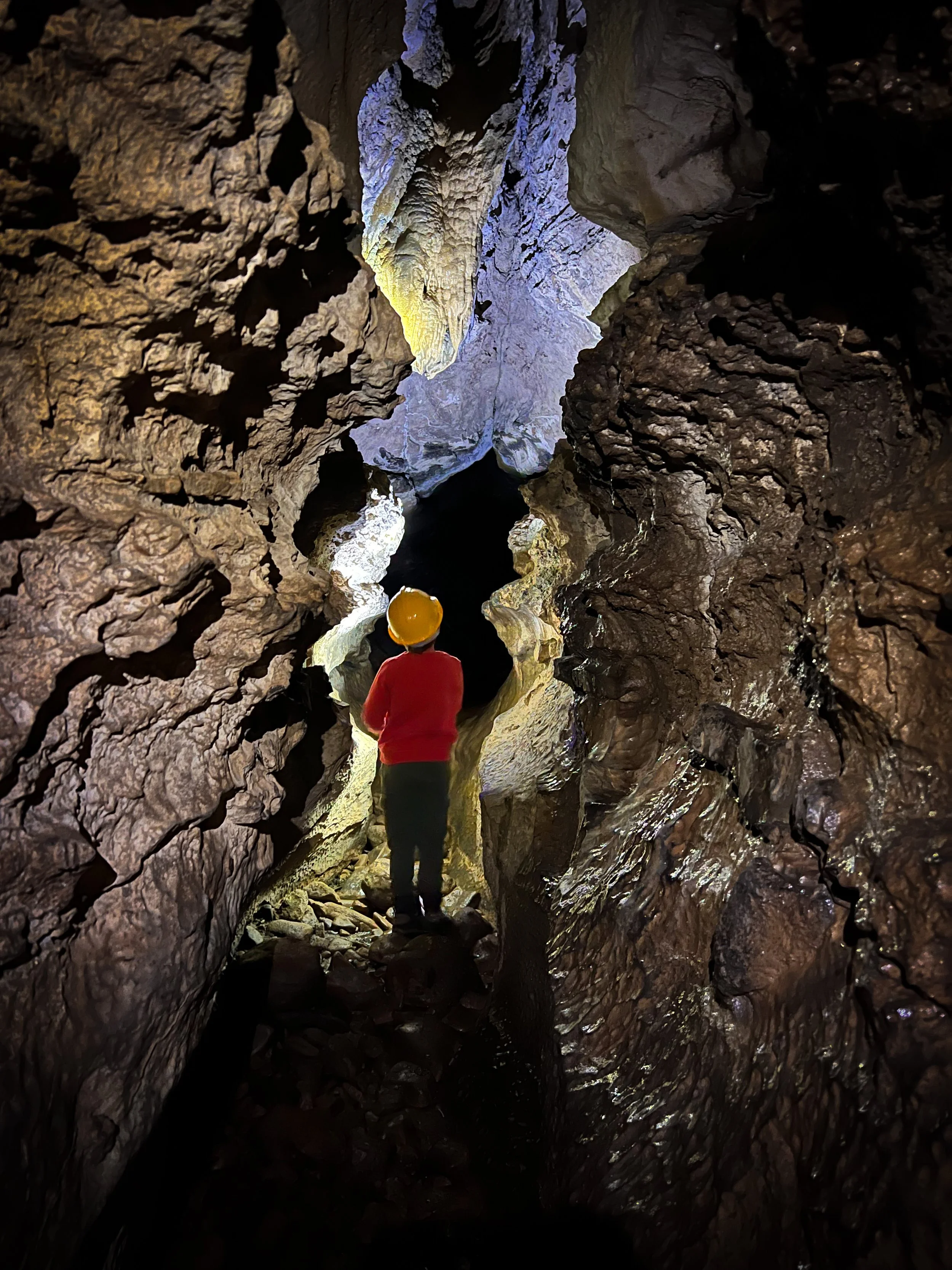 Child walking through a cave with a hard hat on