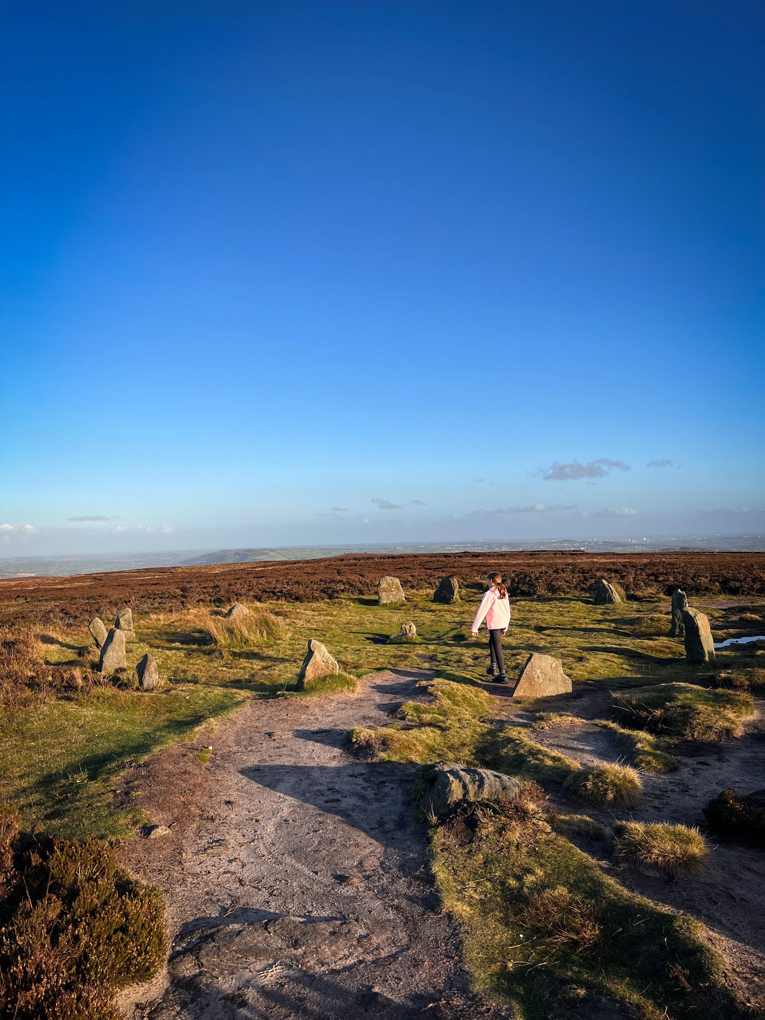 Child walking into a stone circle under blue skies