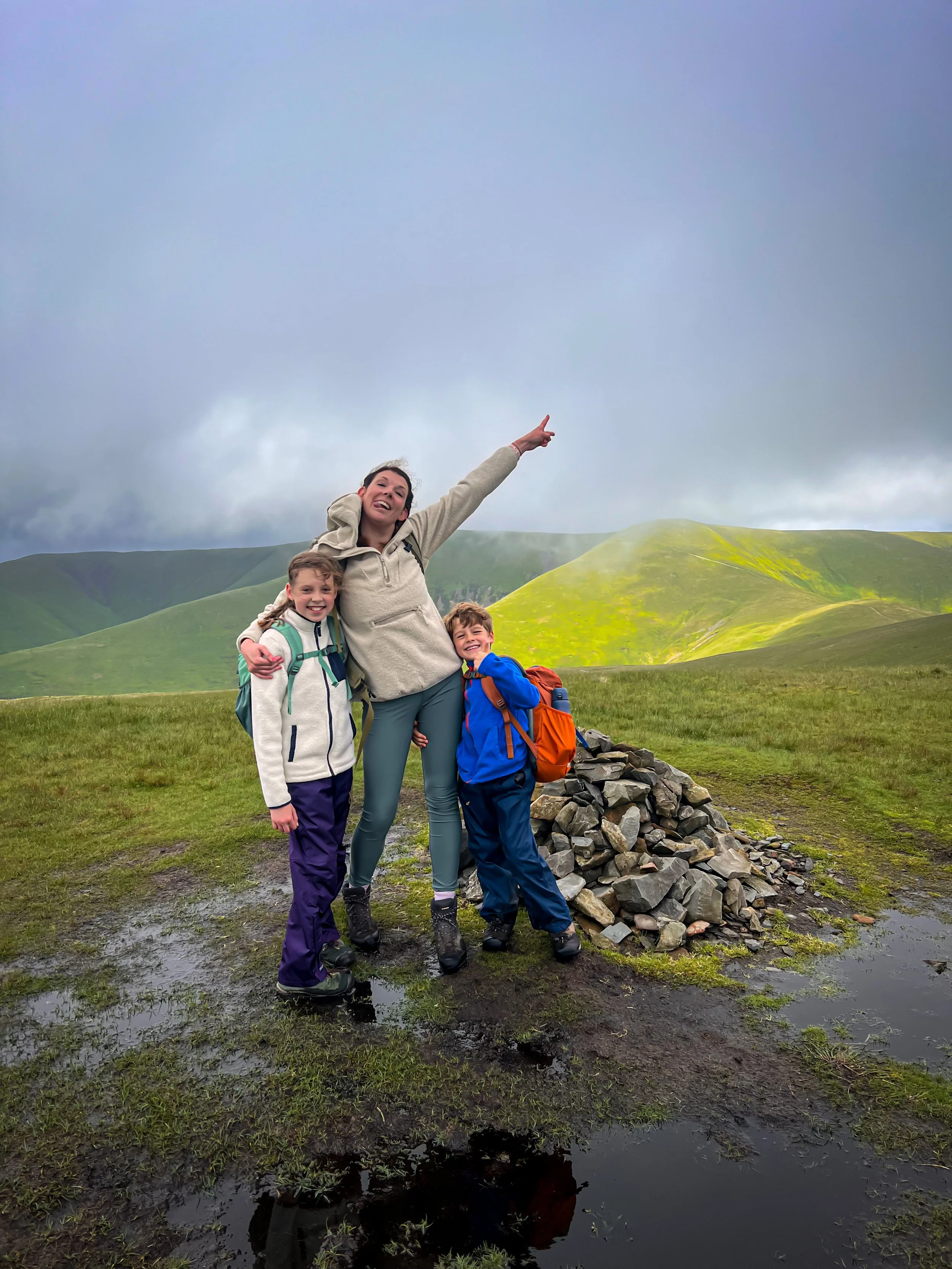 Mum and two kids standing at the cairn of Arant Haw