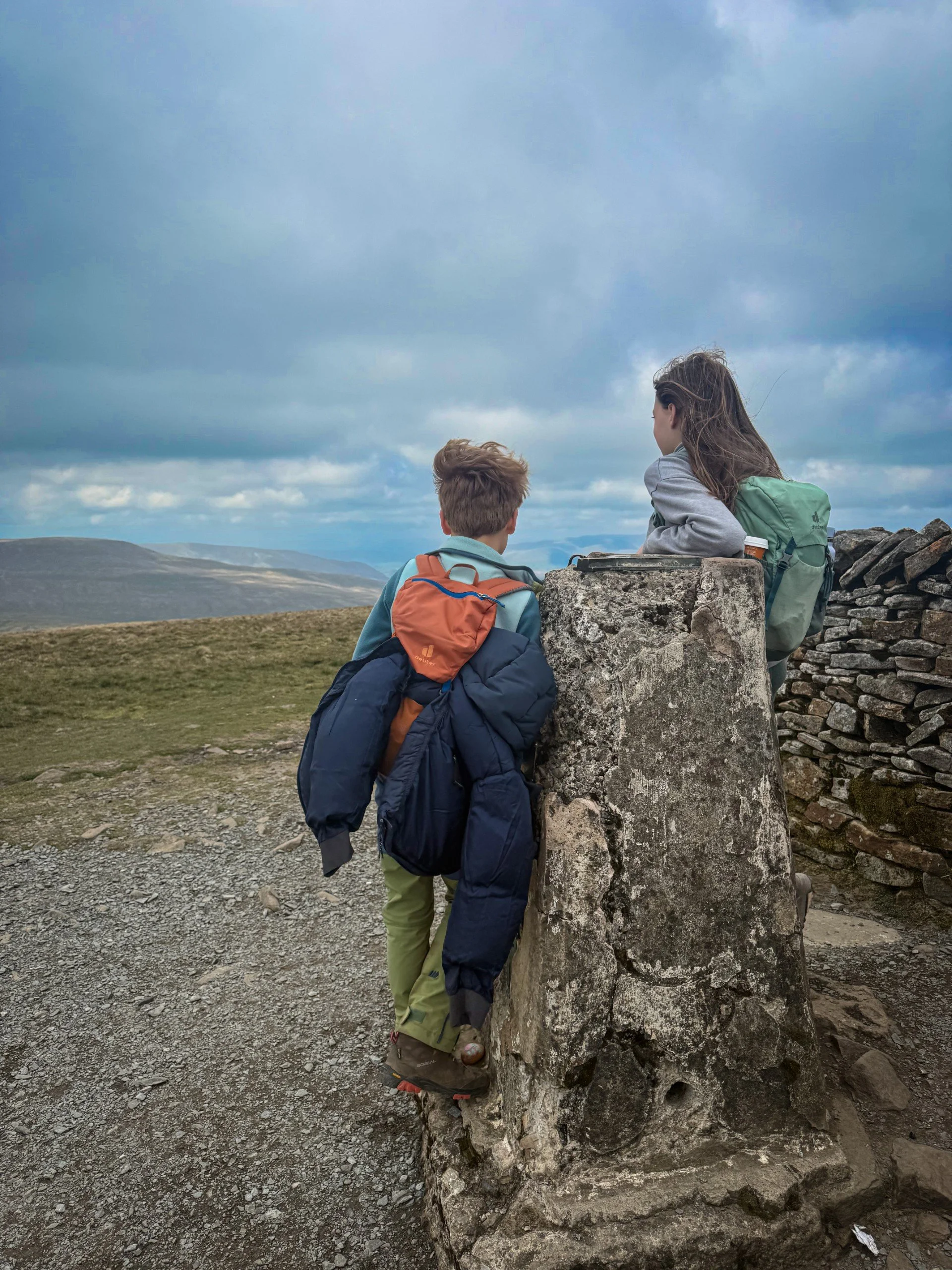Standing at the trig point of whernside with cloudy skies