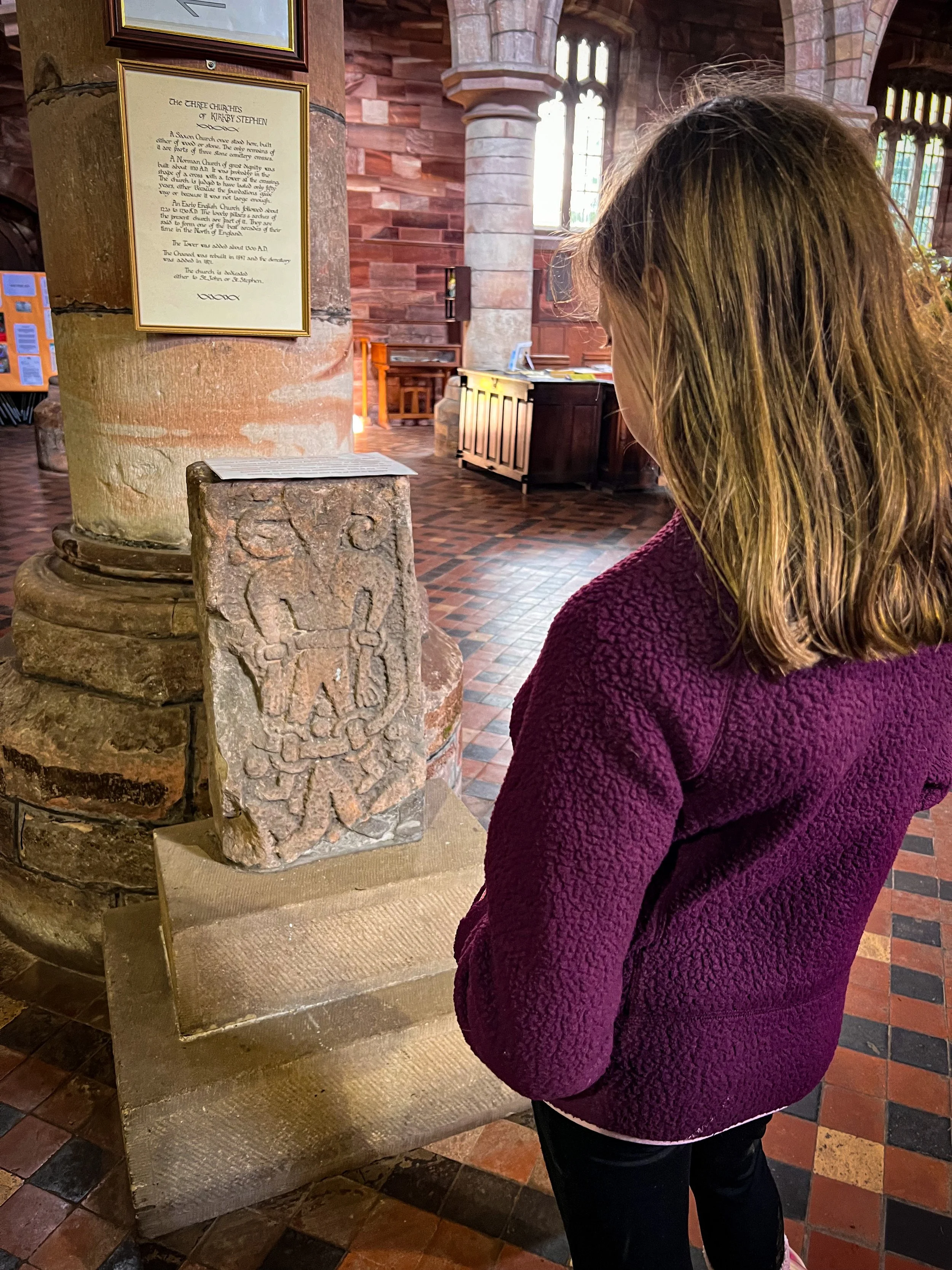 Child in a church looking at a large carved stone