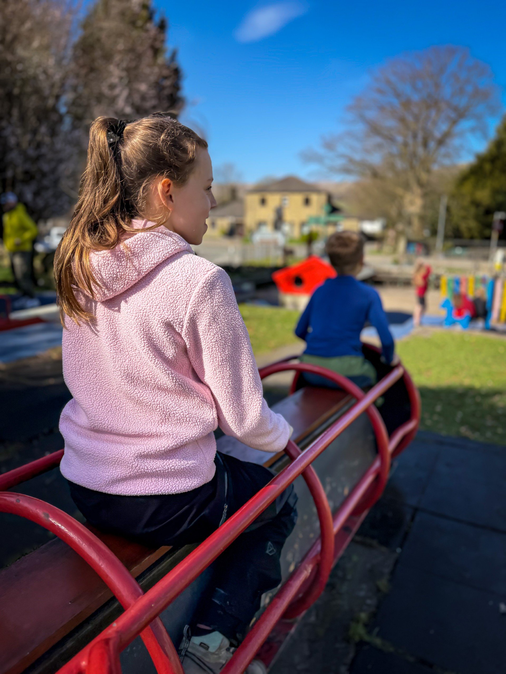 Children sitting on a play park in sunshine