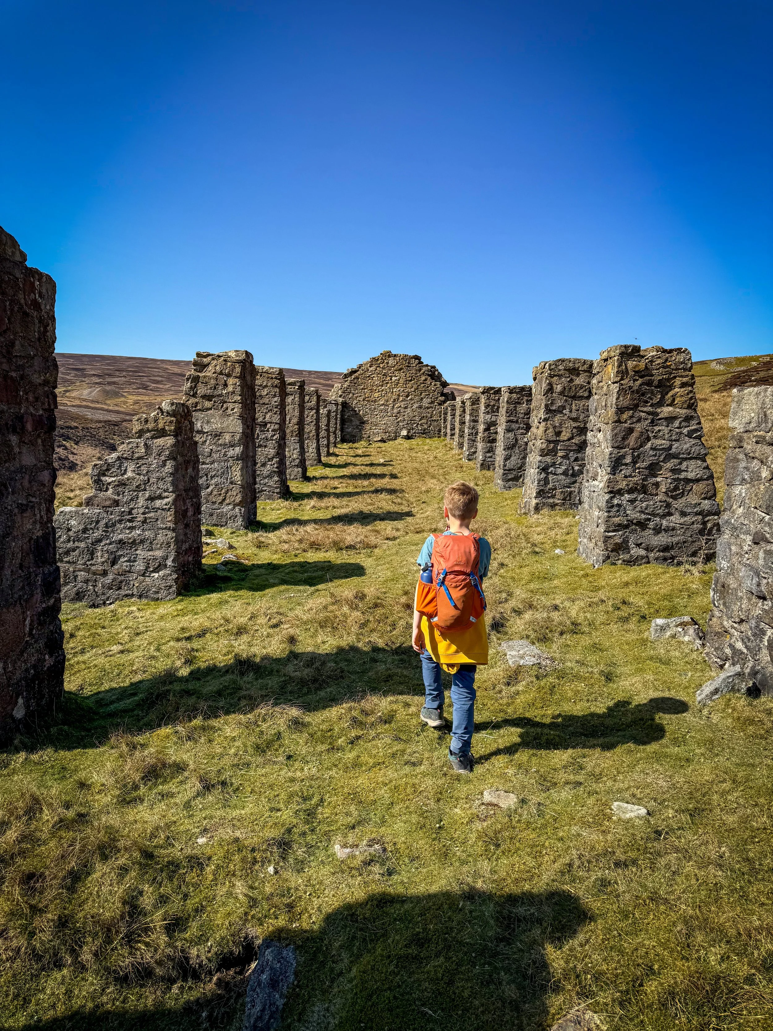 Child walking through the columns of an old ruined smelt store