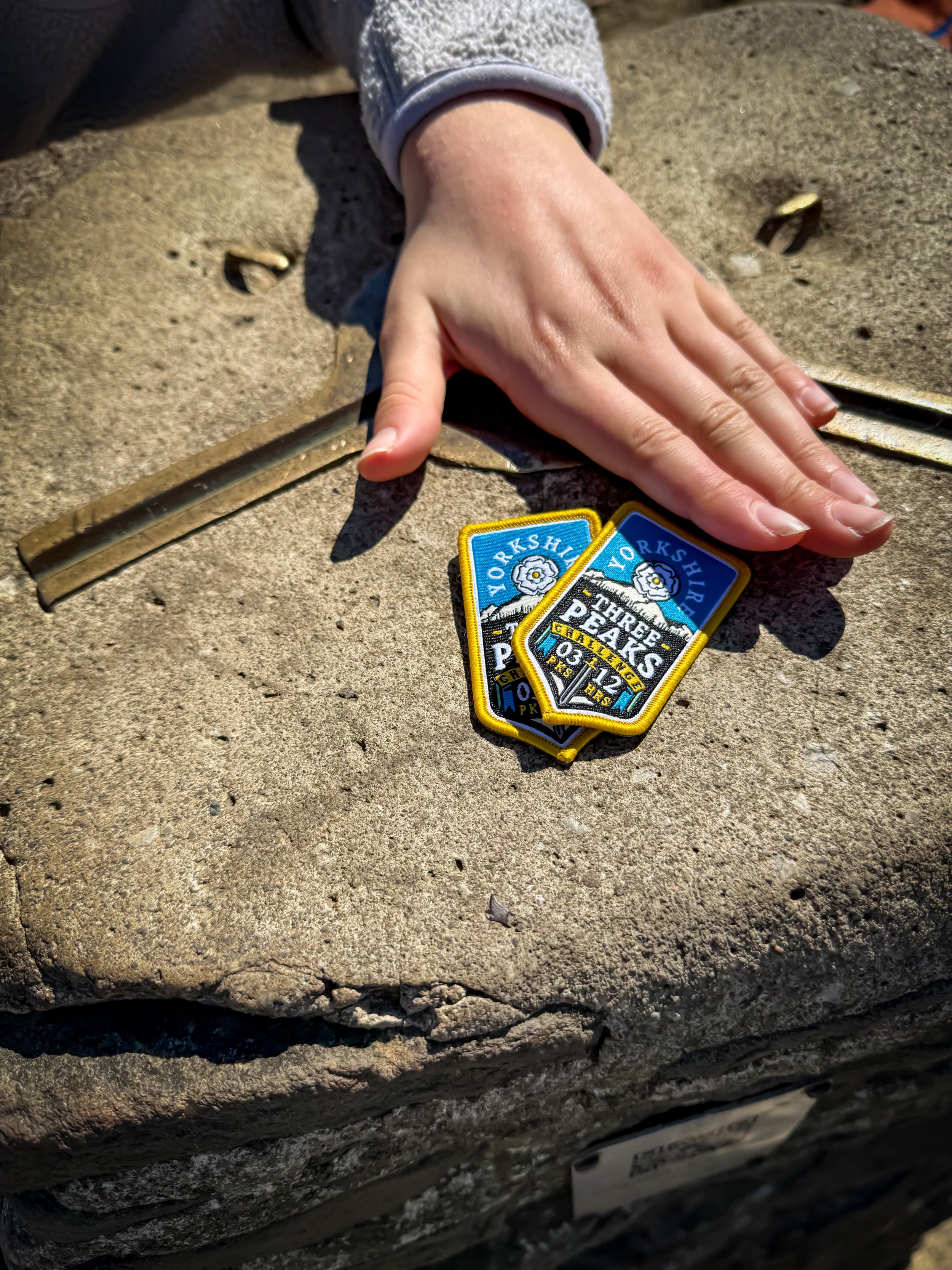 Yorkshire Three Peaks badges on a trig point