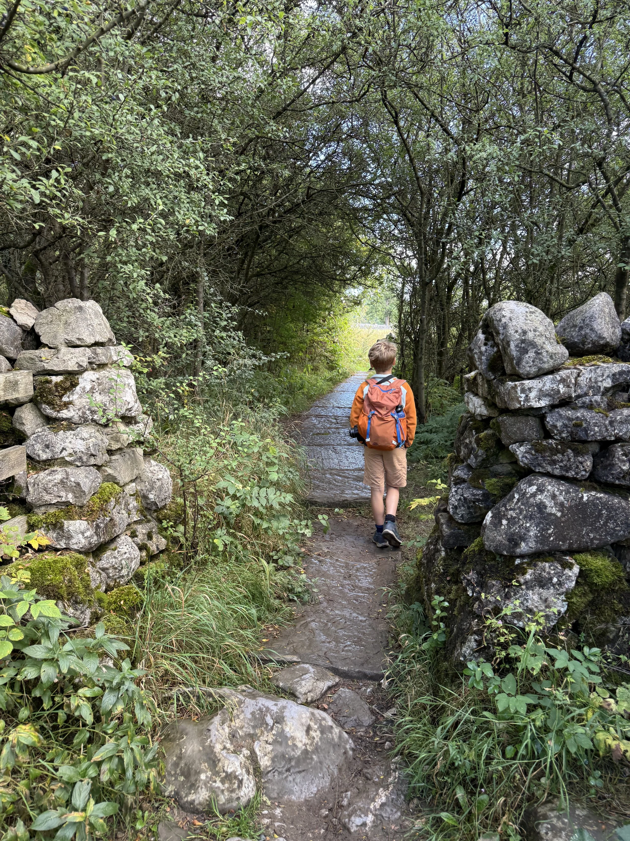 Child walking through a wall on a paved area