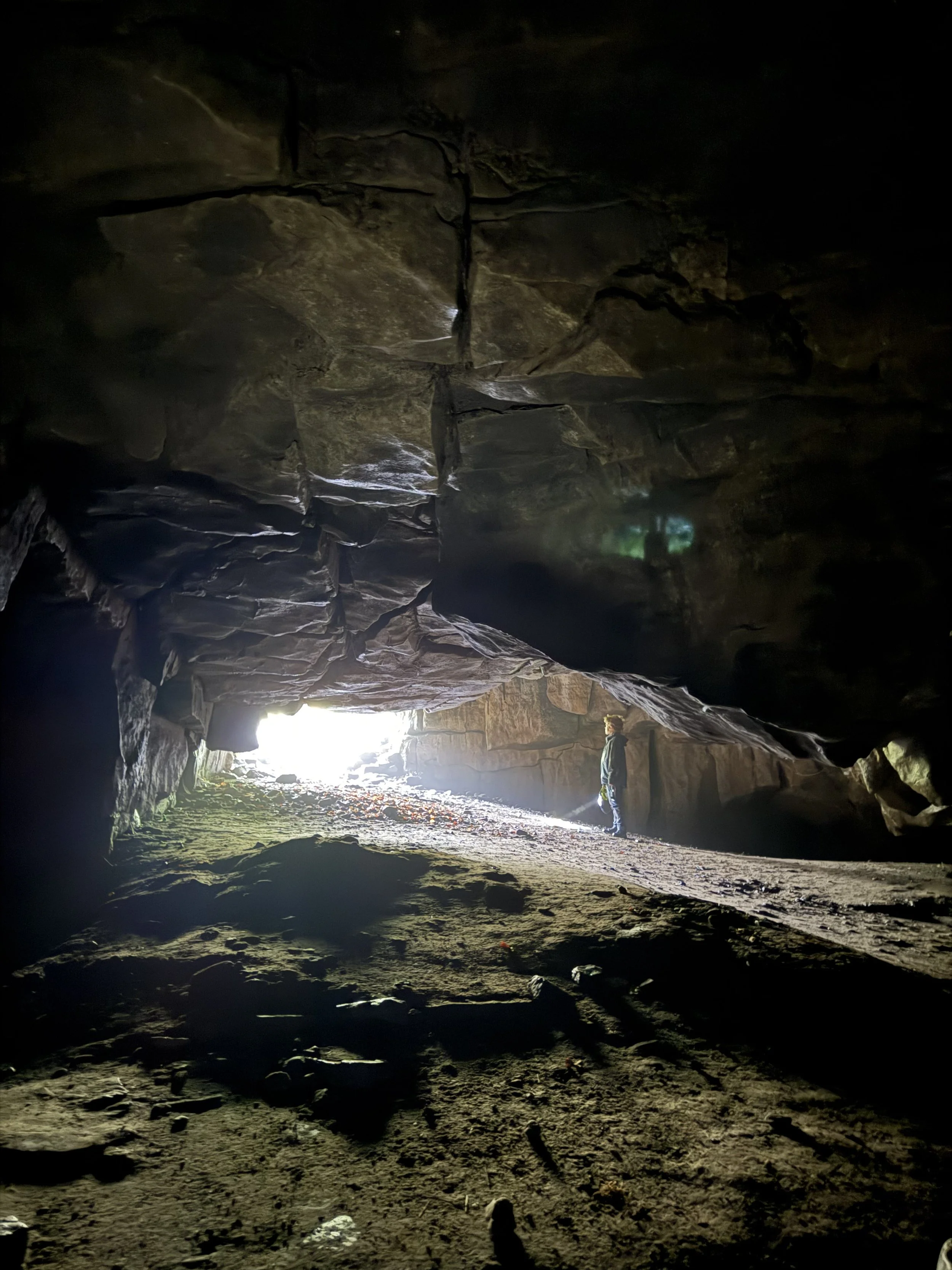 Child in cave entrance with light pouring in and holding a torch