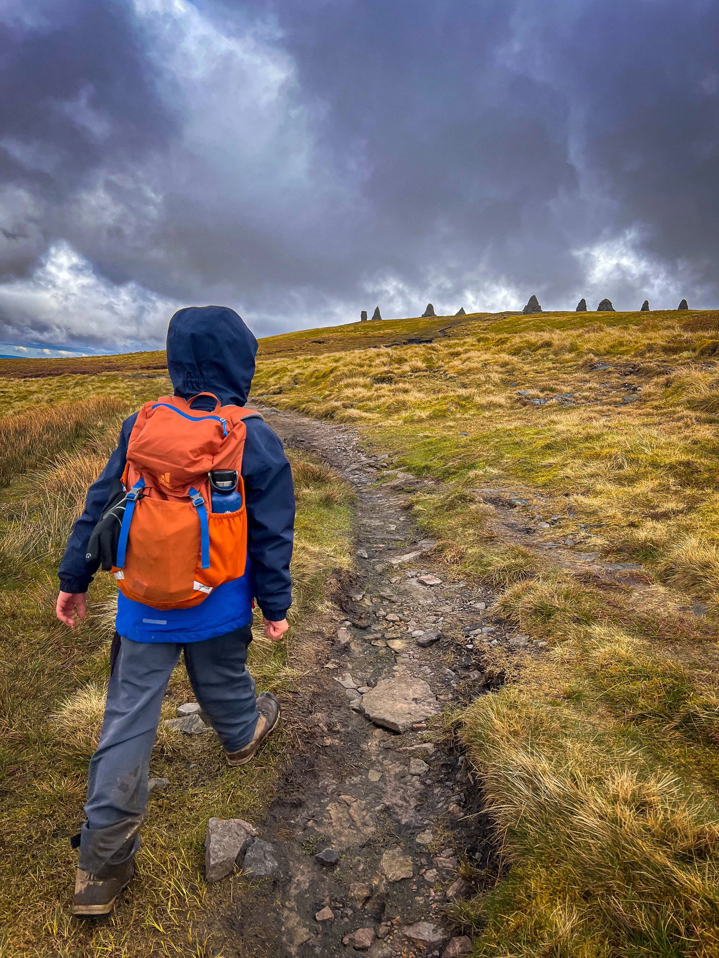 Child walking towards cairns on the ridge line