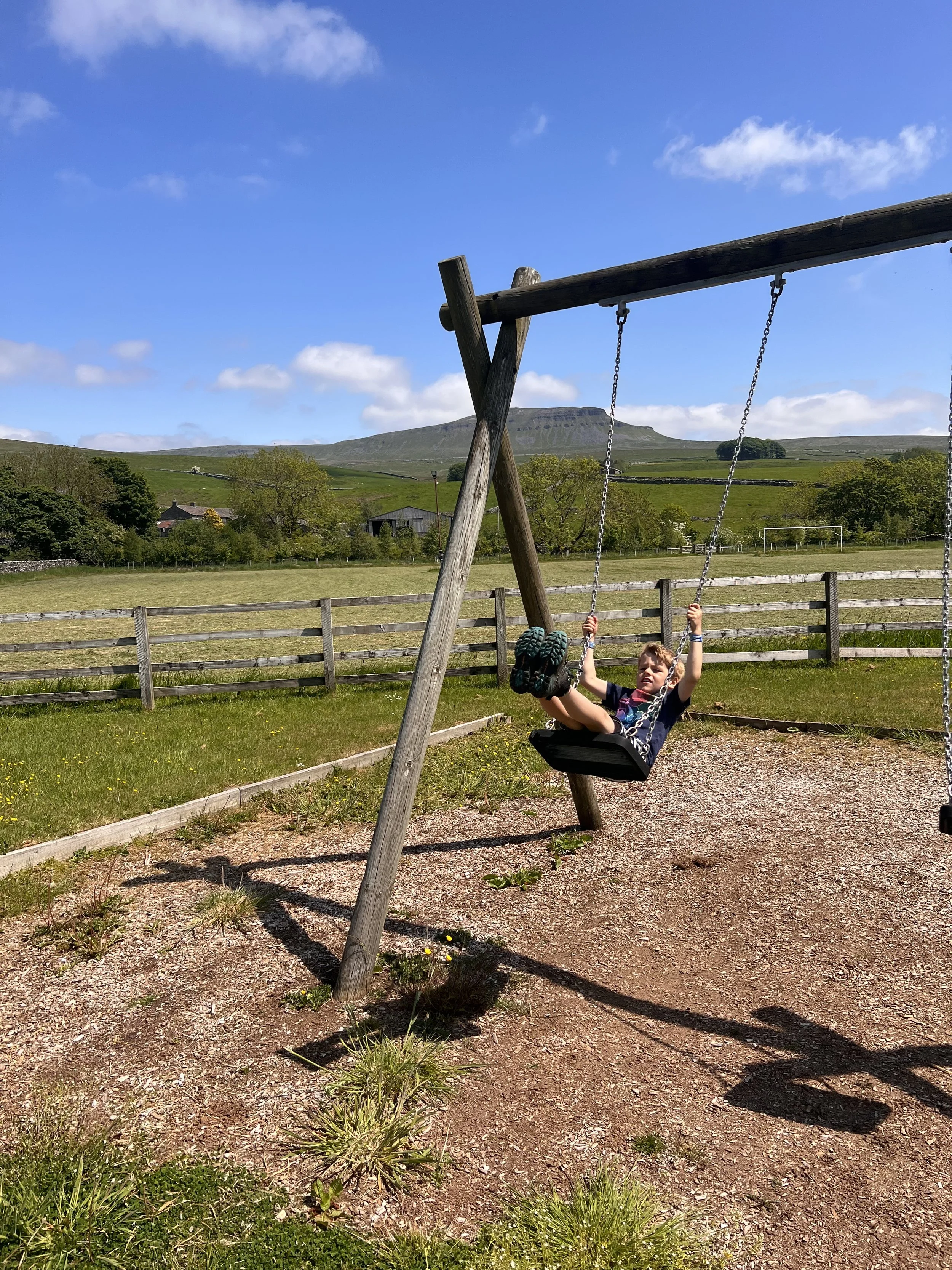 Child swinging on swings with view of mountains in the background