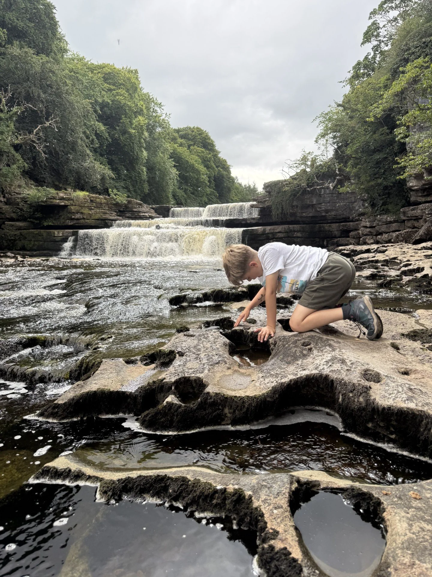Child playing at the side of a waterfall