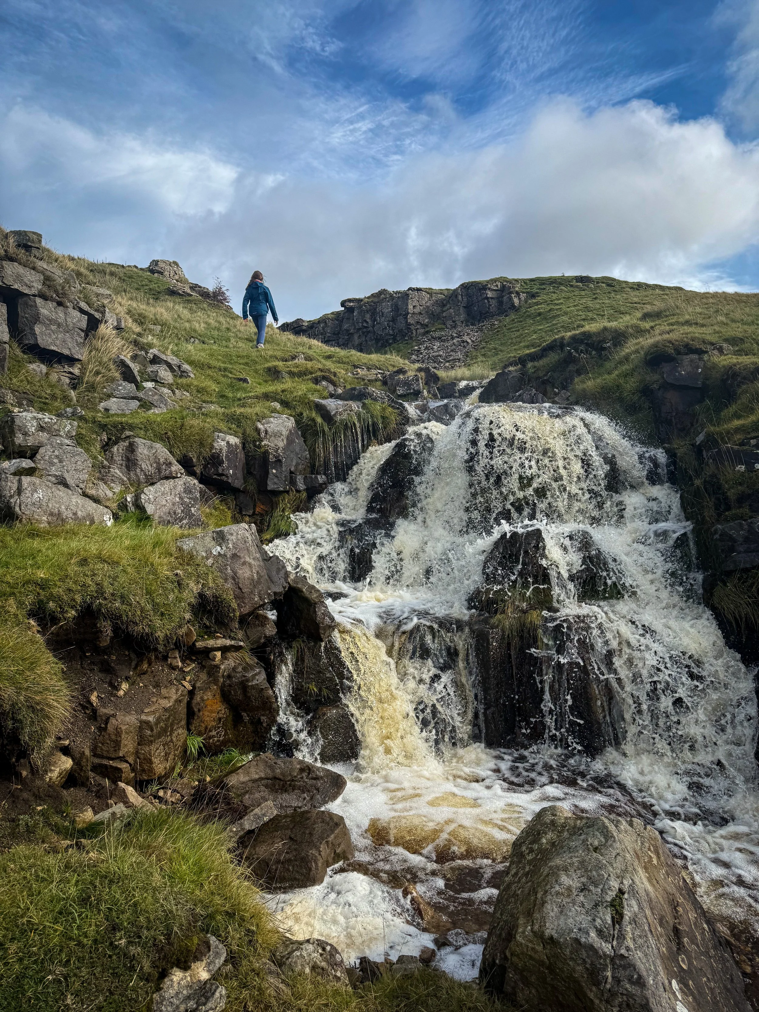 Child walking up a waterfall which is in full force