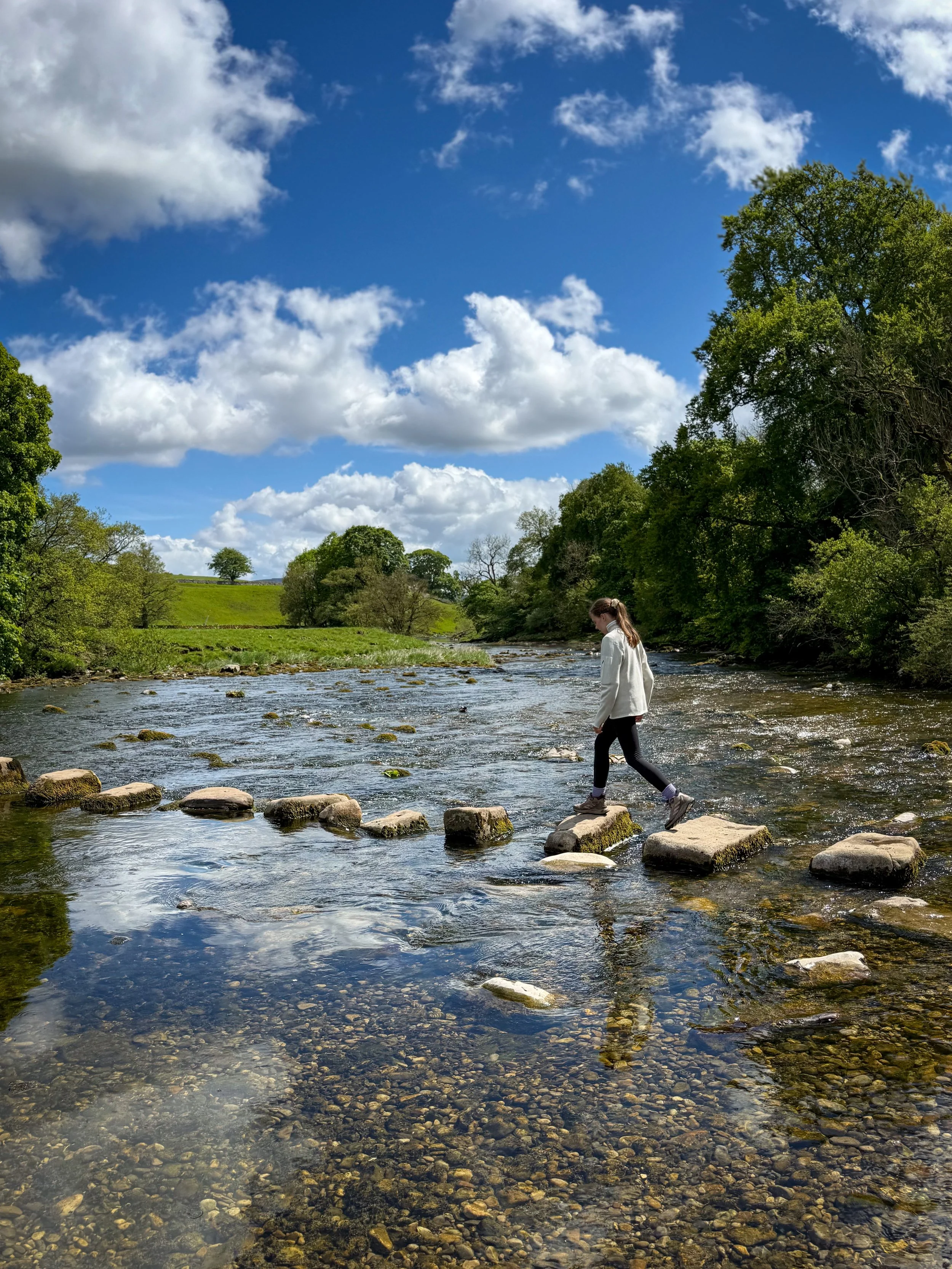 Child walking across stepping stones in a river