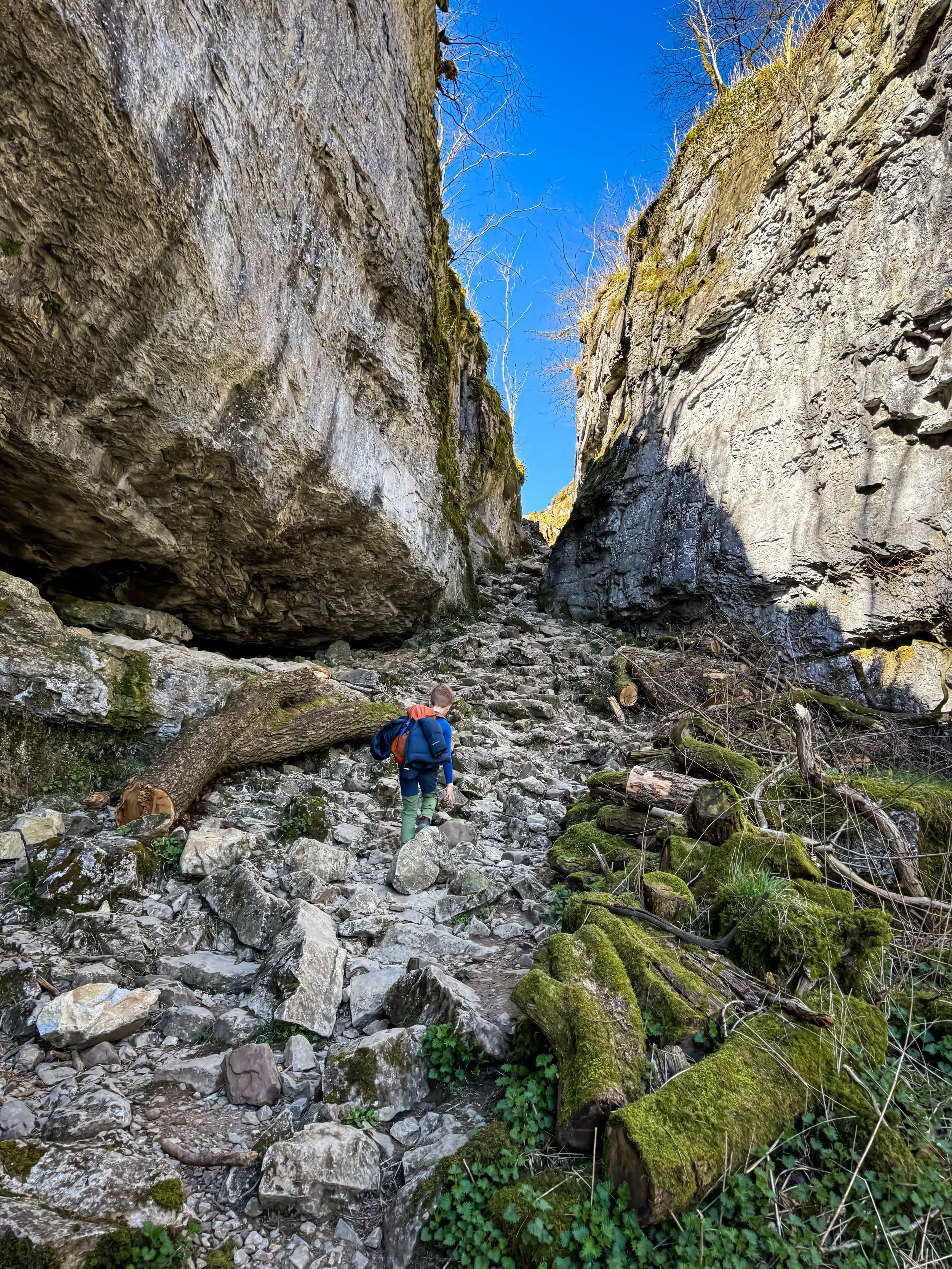 Child walking through the middle of a rocky gorge with towering sides and a narrowing exit point