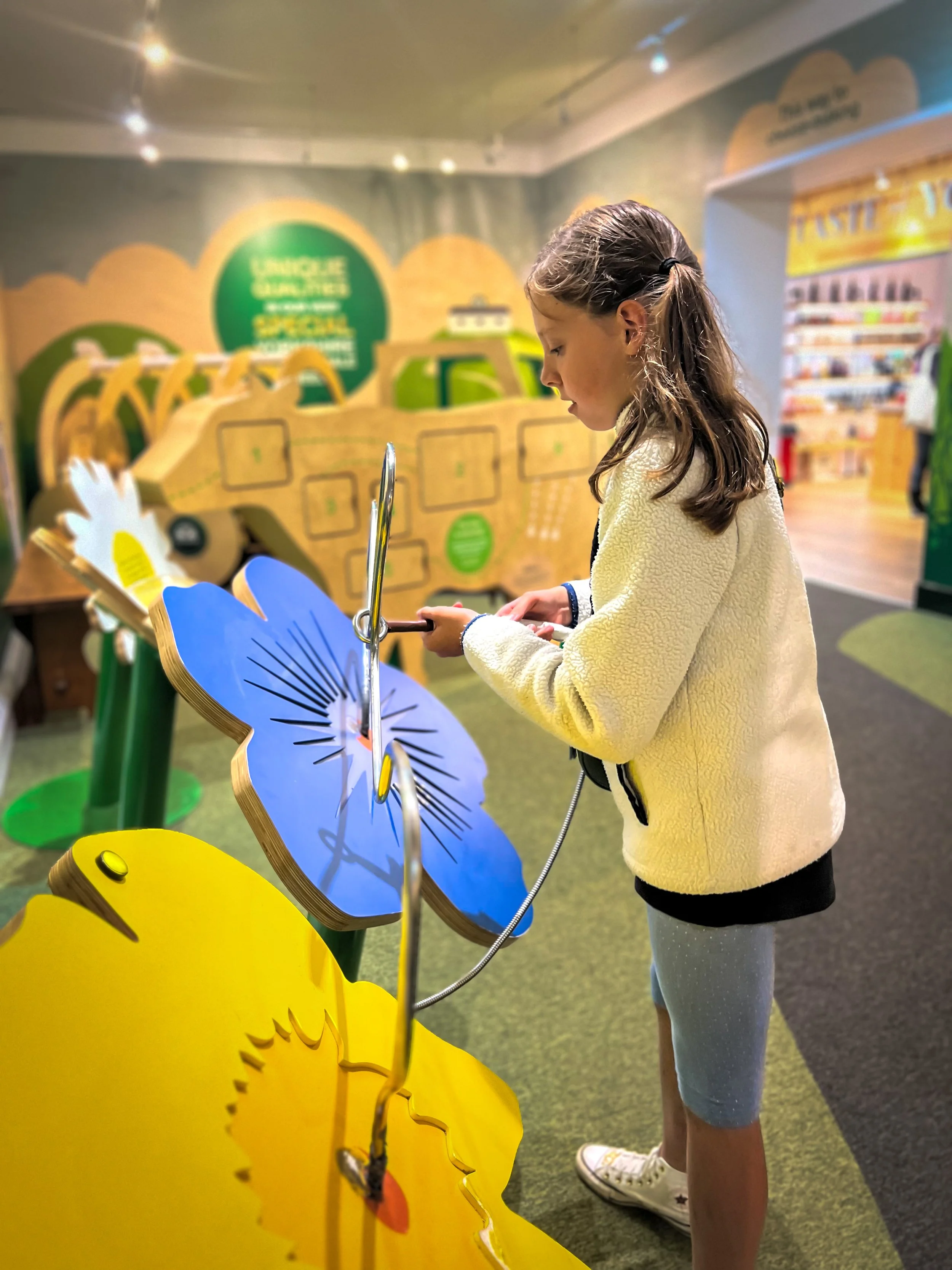 Child playing with a green and yellow flower game in museum