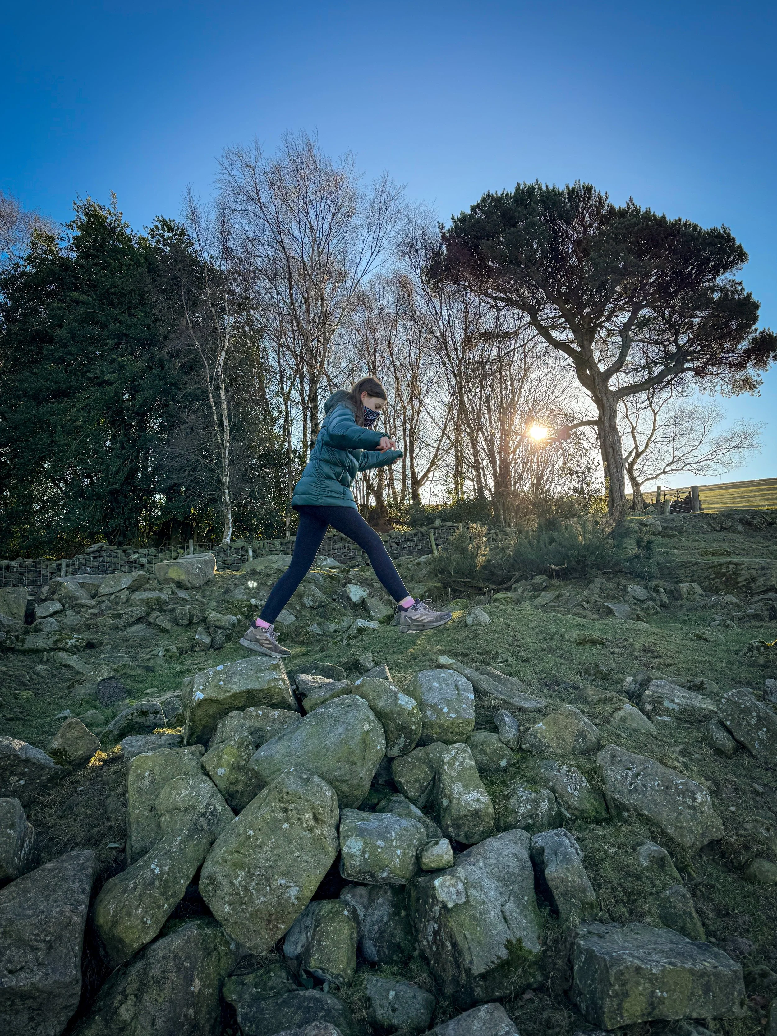 Child leaping across rocks with blue sky behind