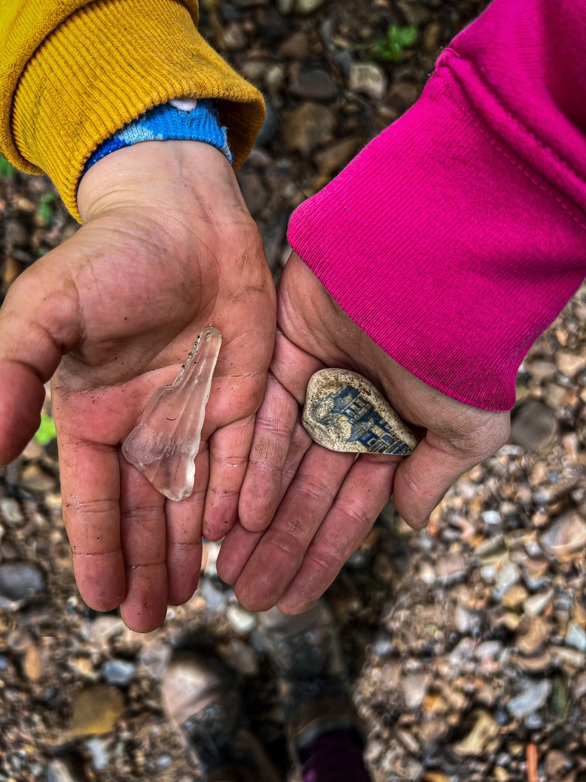 Two children with arms outstretched holding pottery pieces on their palms