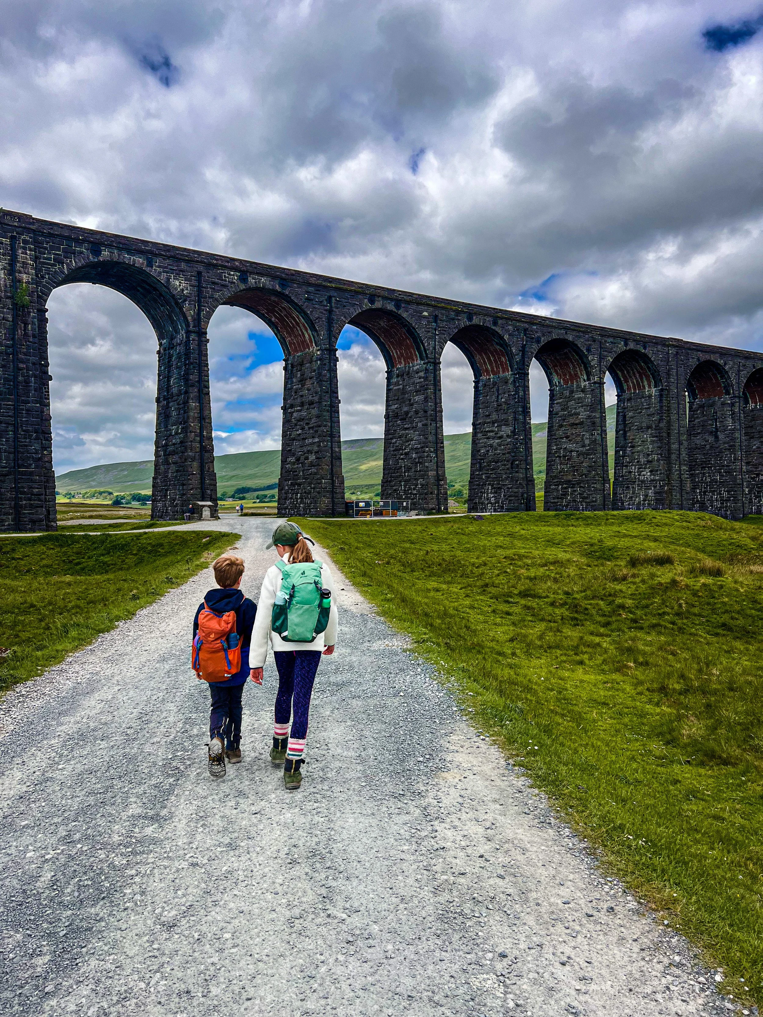 Two children walking towards the Ribblehead Viaduct in Summer