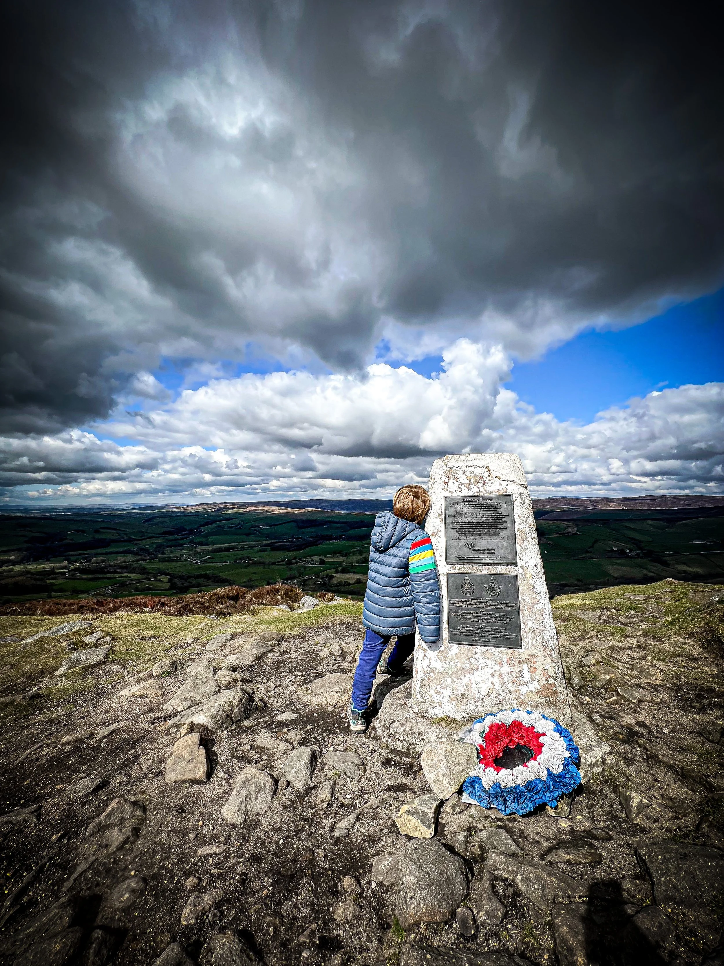 Beamsley Beacon trig point with child leaning up against it