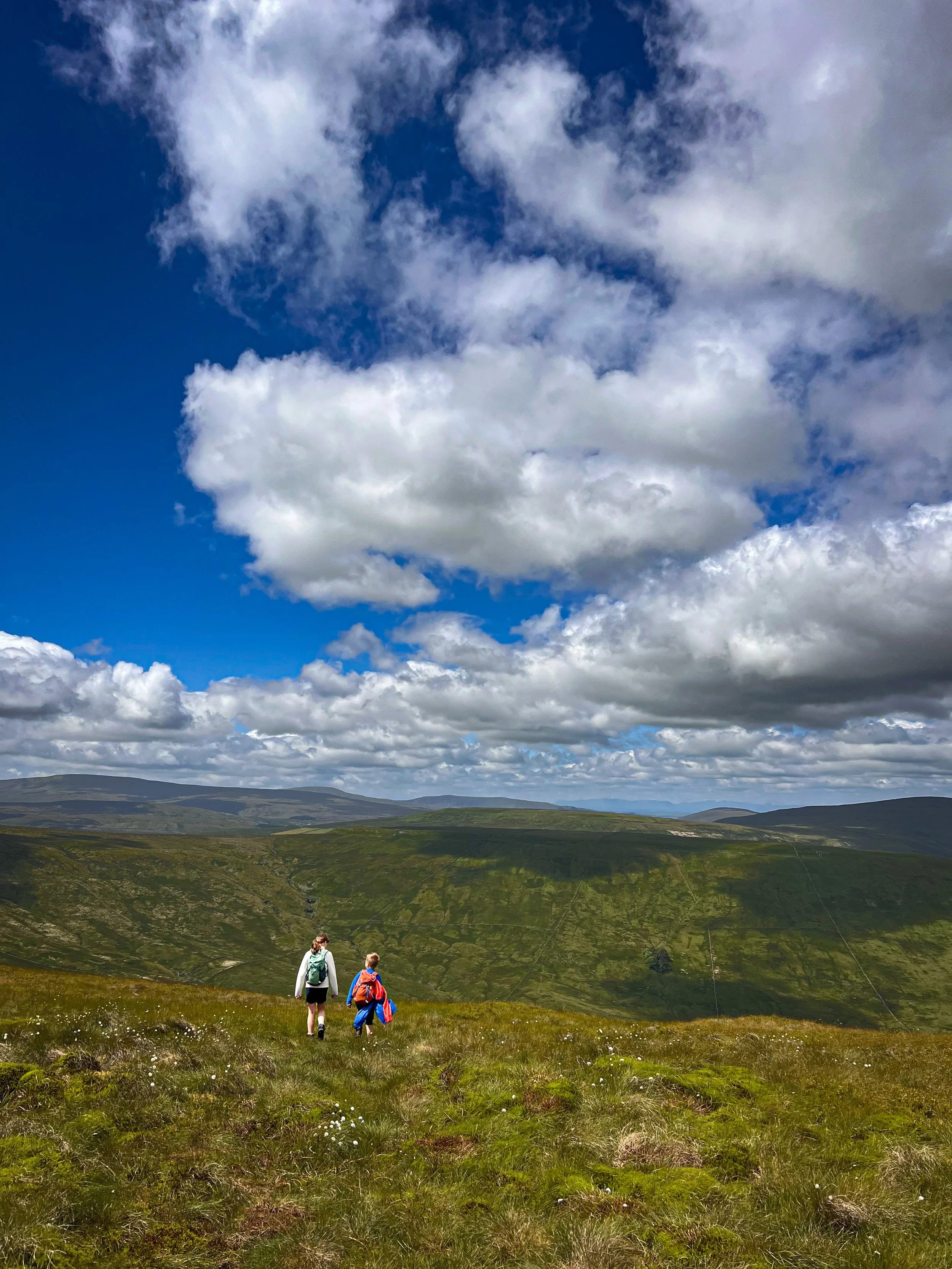 Two children walking with blue skies and mountain views beyond