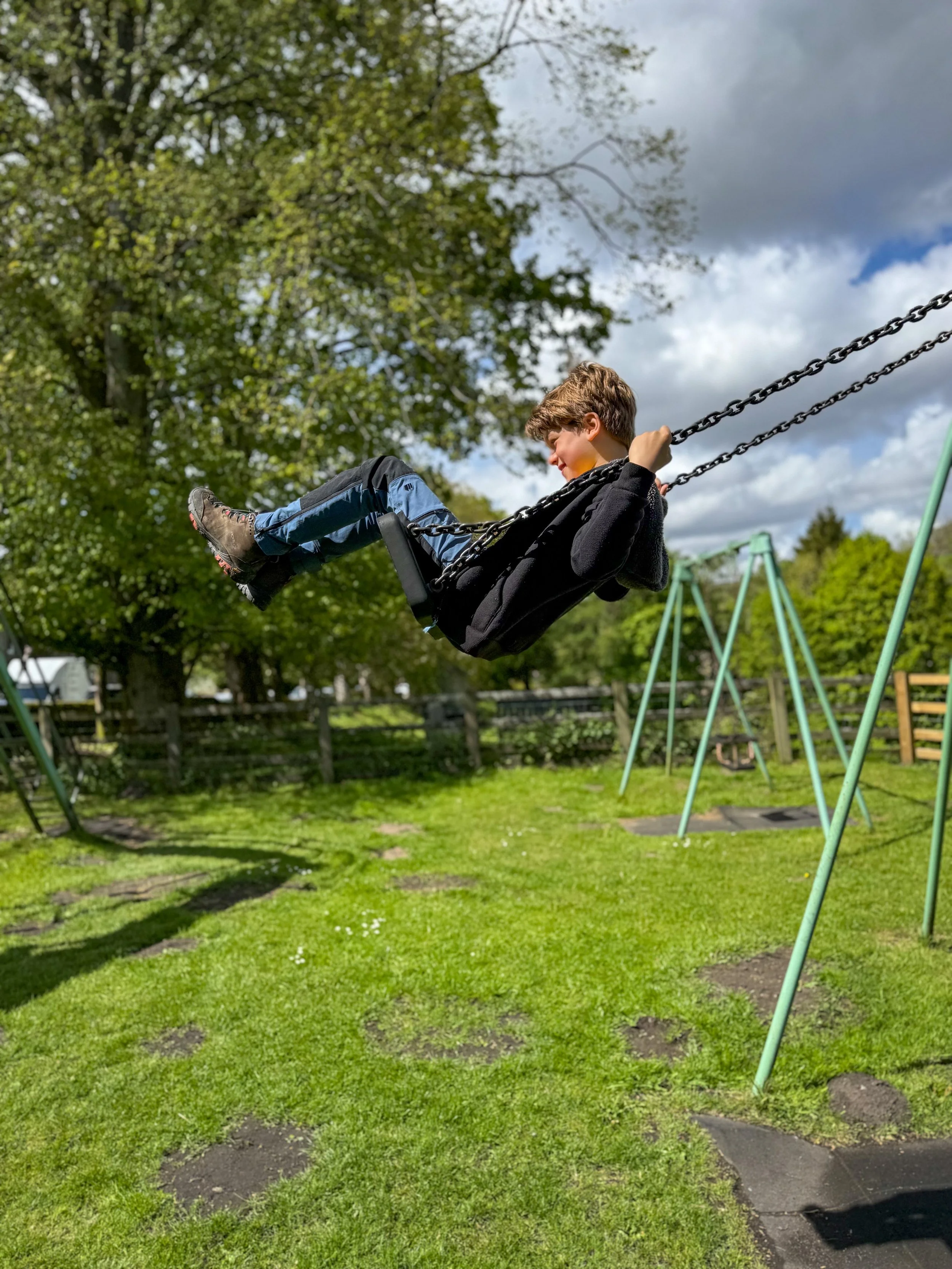 Child sitting on a swing swinging up high