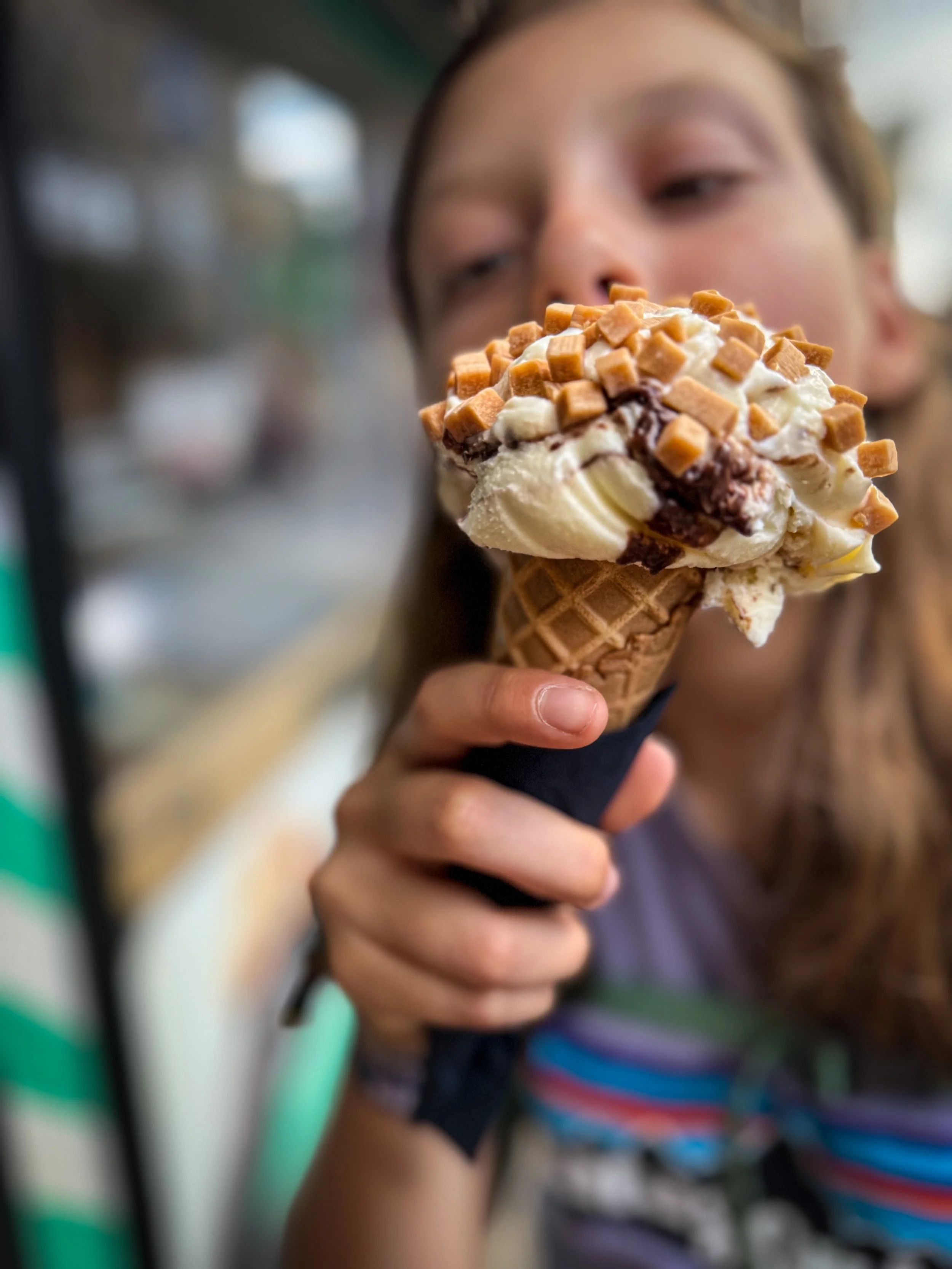 Child eating an ice cream covered in fudge pieces