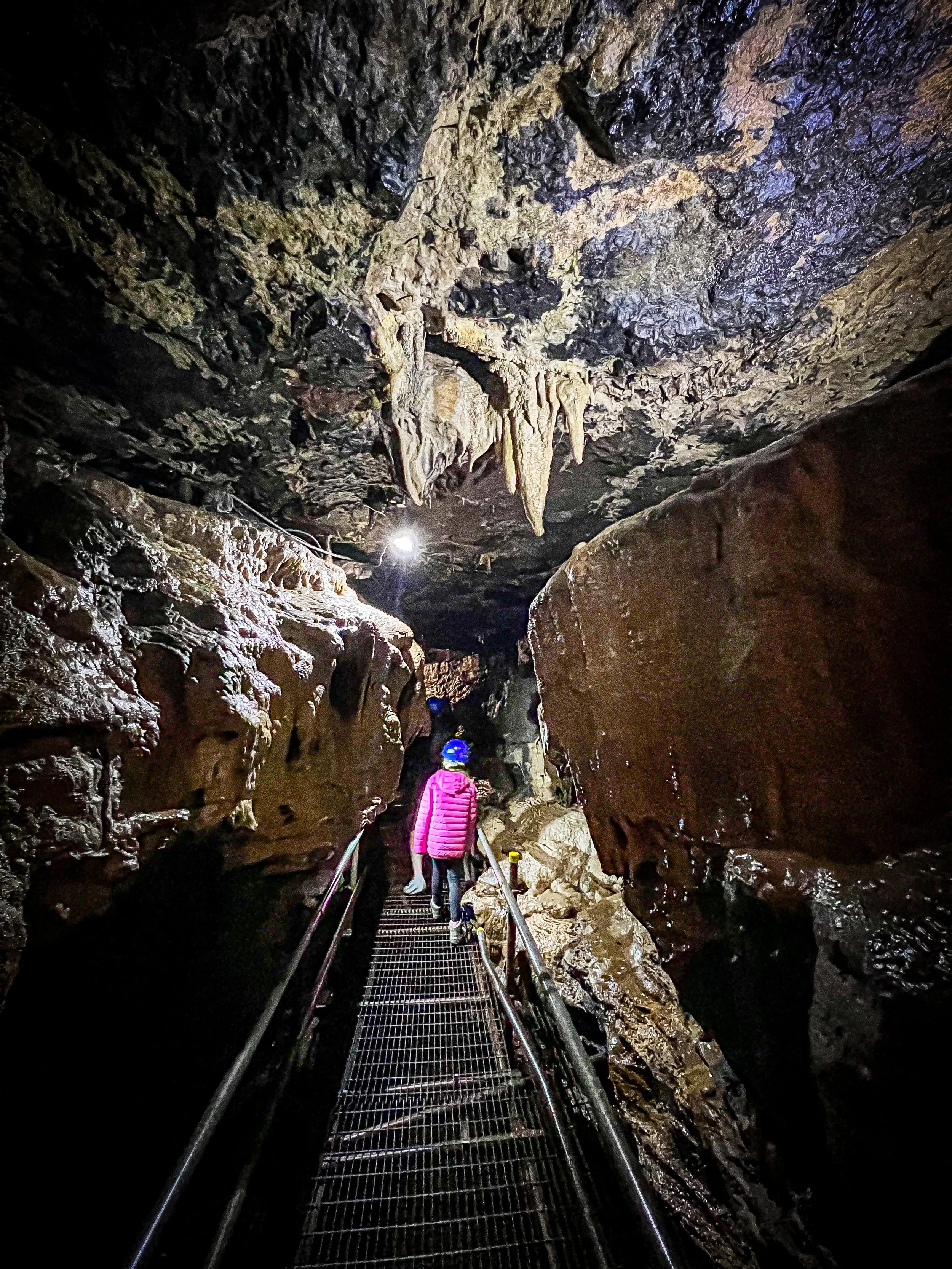 Child walking along a metal walkway inside a cave