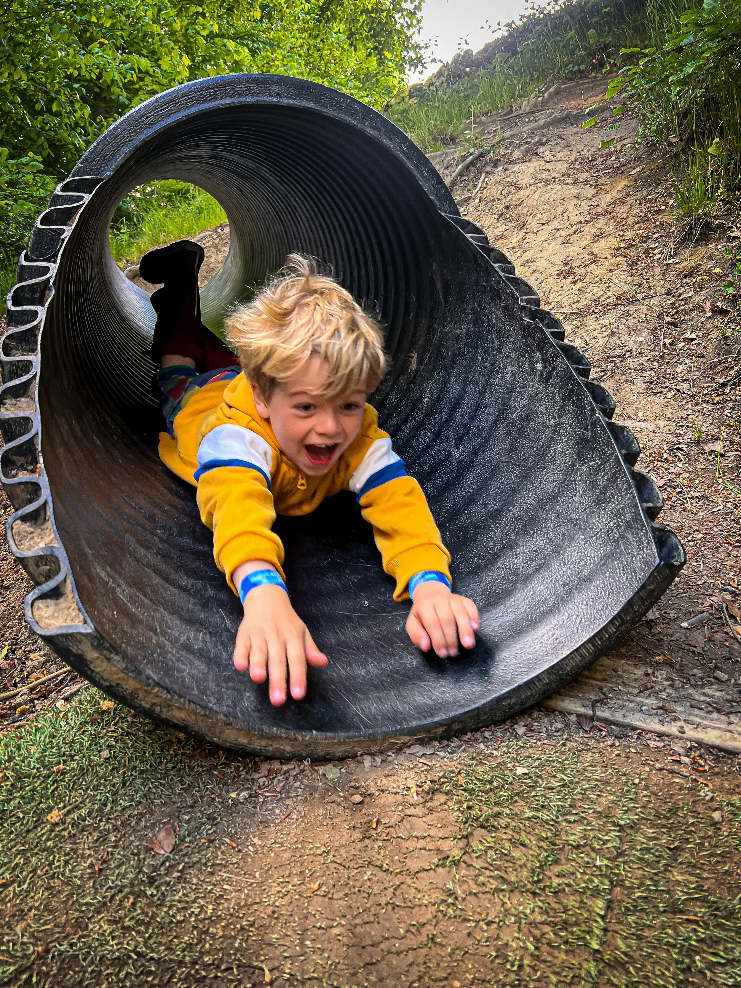 Child sliding down a black tube slide