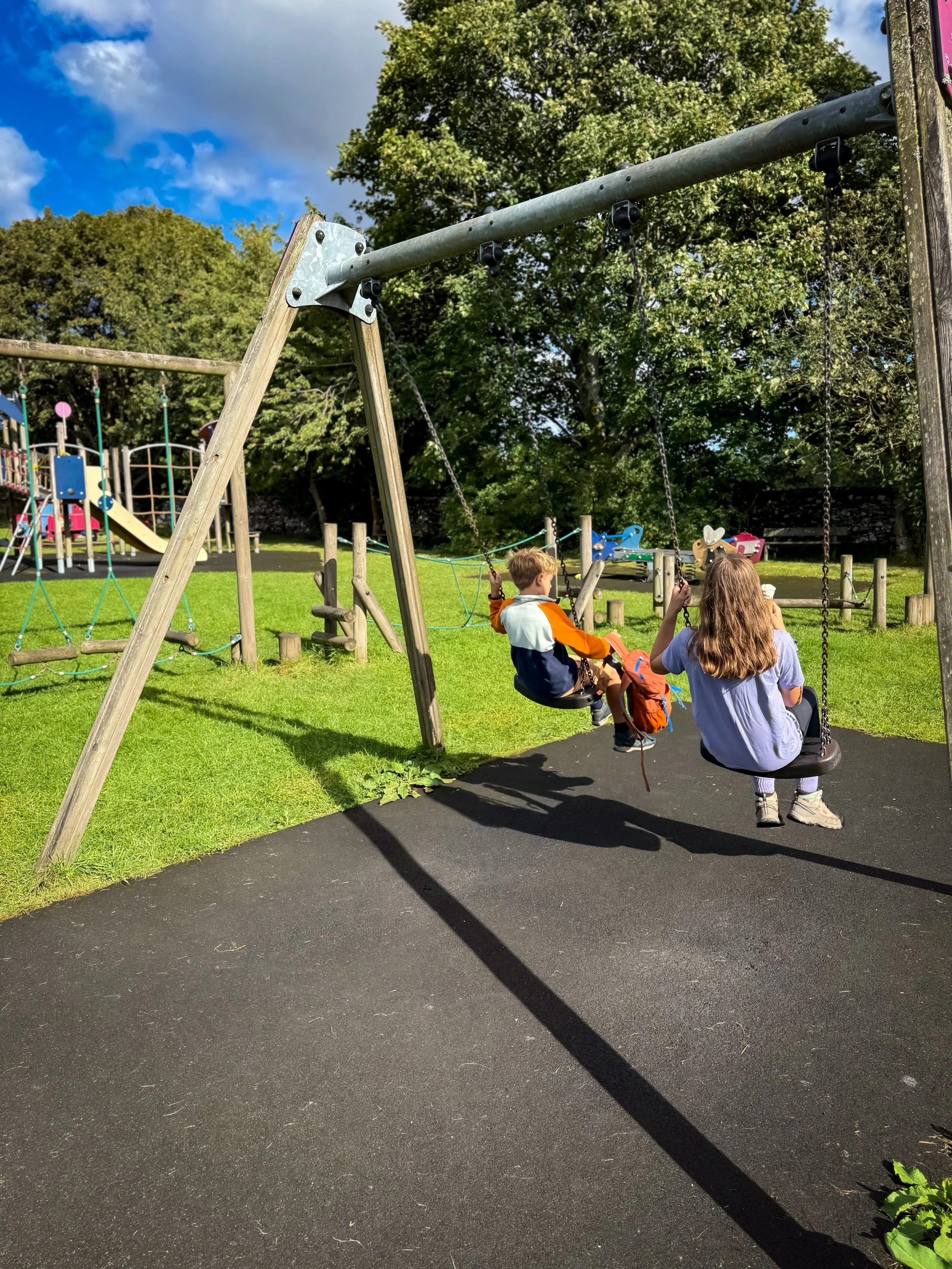 Children sitting on swings in the play park