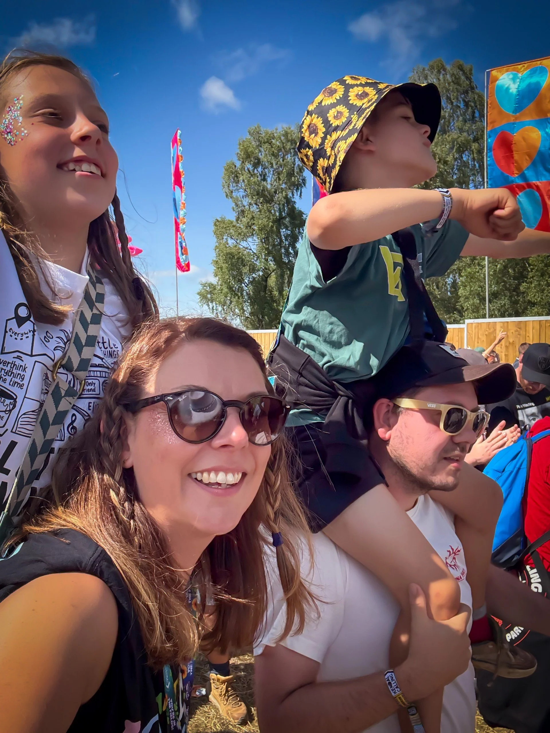Two adults with two children sat on shoulders under blue skies