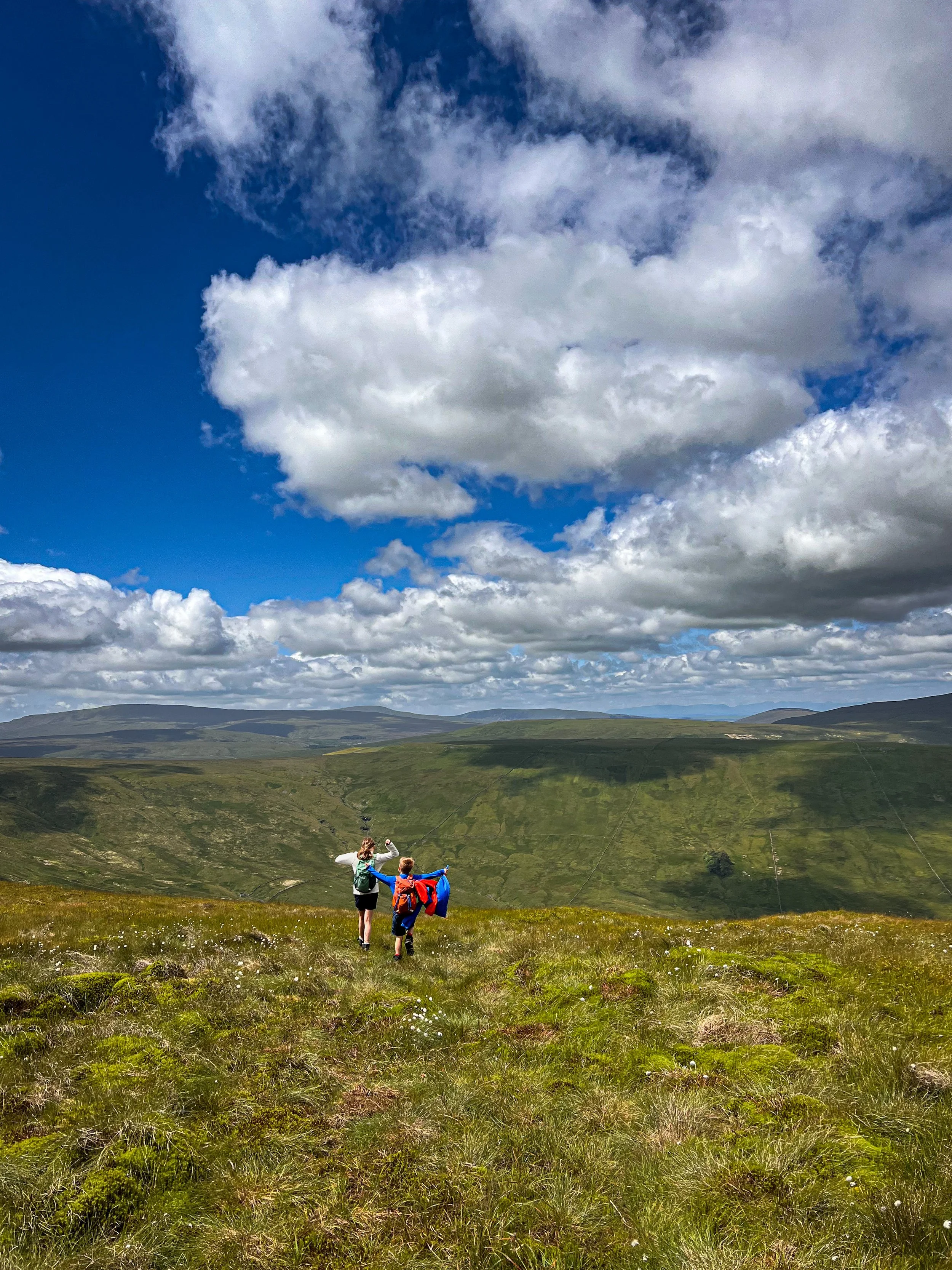 Two Children with arms in the air with mountain views beyond
